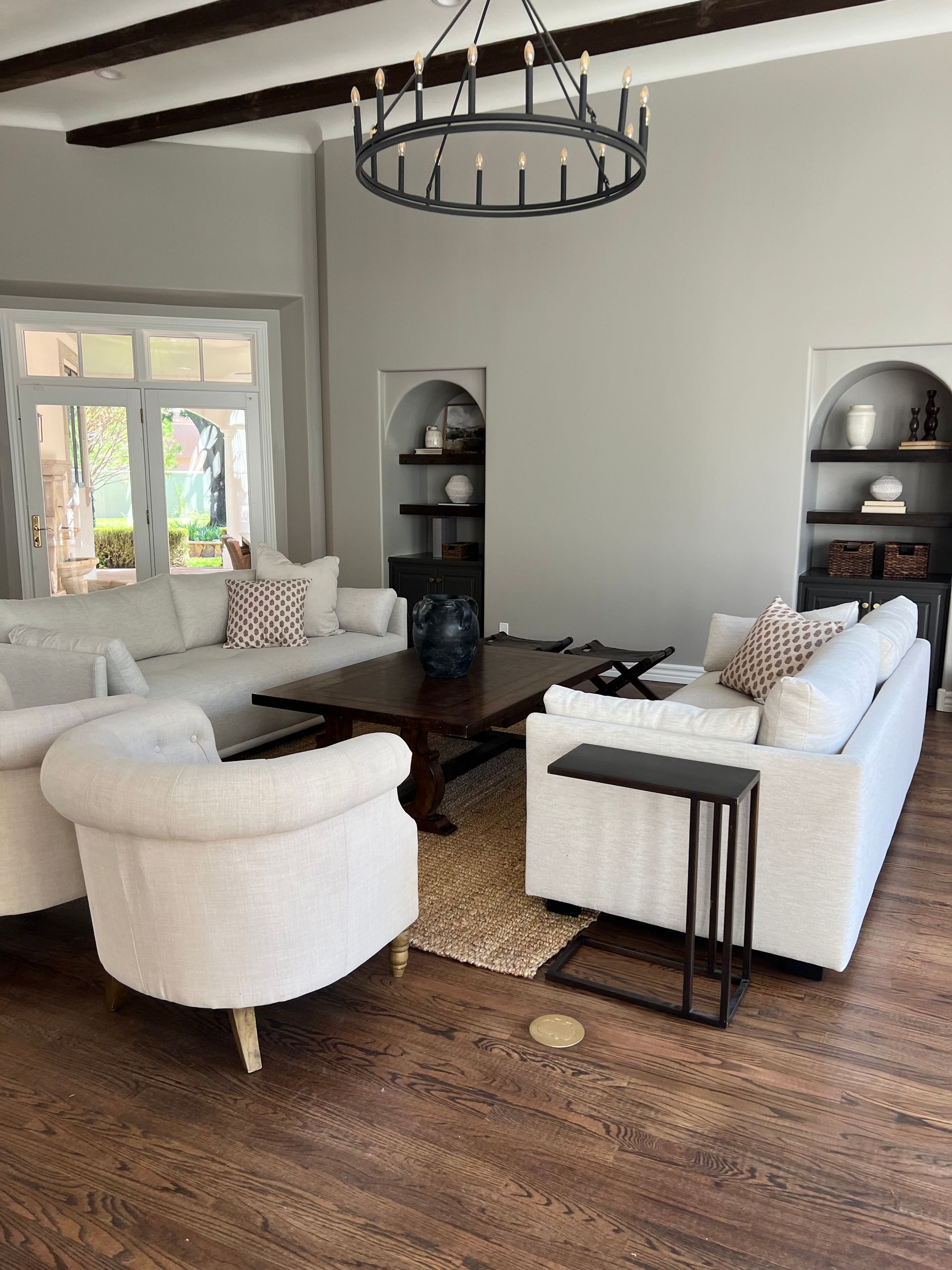A living room with white furniture and a chandelier hanging from the ceiling.