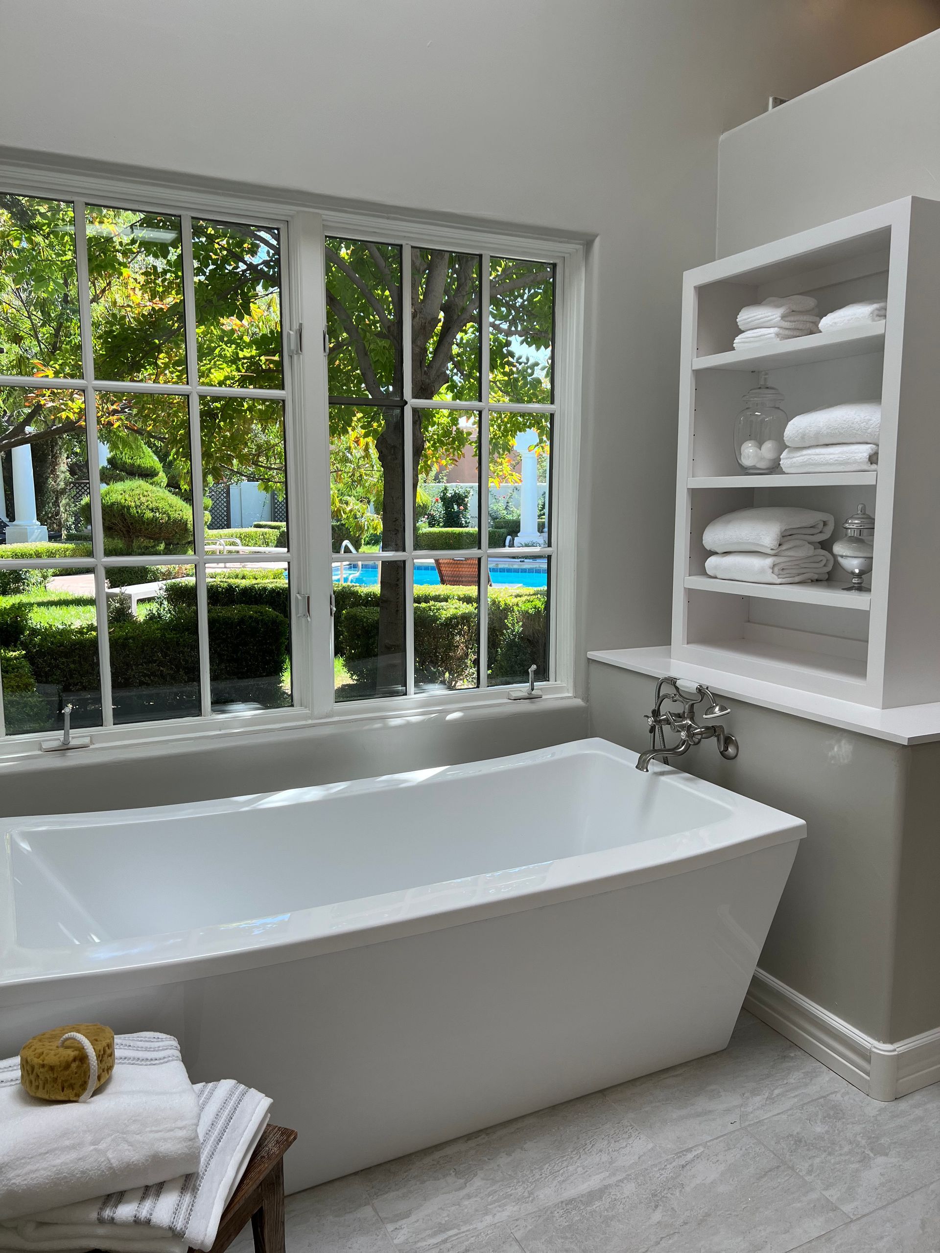 A bathroom with a tub and a window with a view of a pool