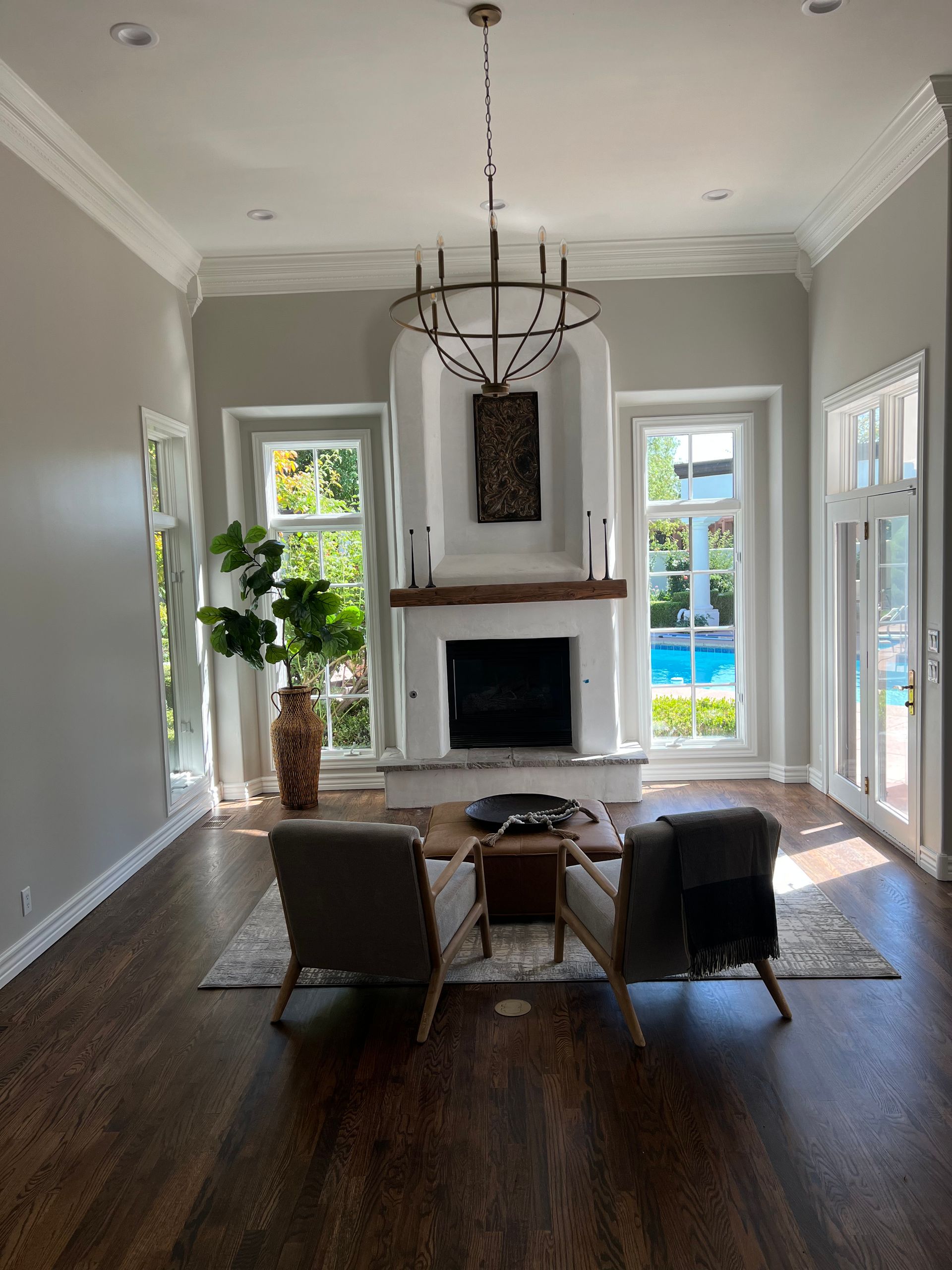 A living room with two chairs , a fireplace and a chandelier.