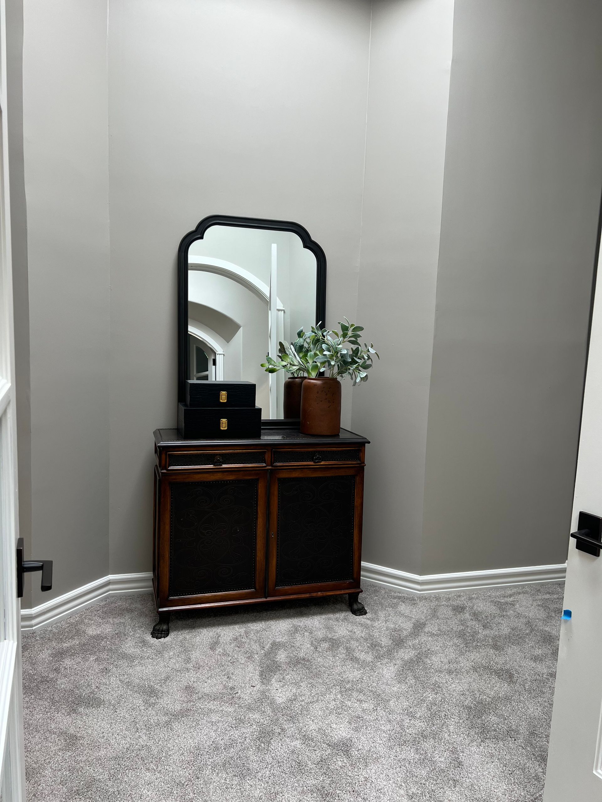 A corner of a room with a mirror and a dresser.