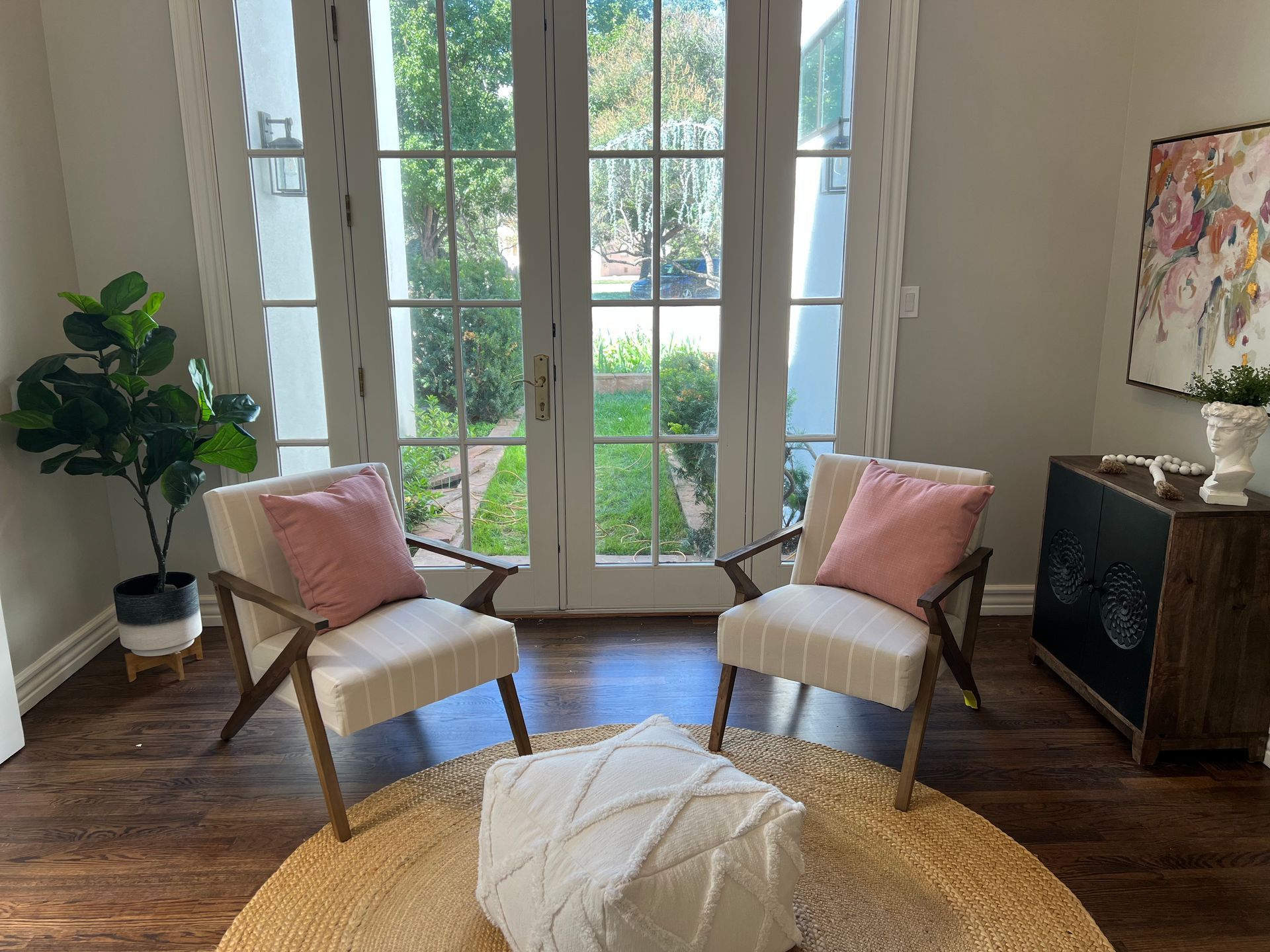 A living room with two chairs and two ottomans in front of a window.