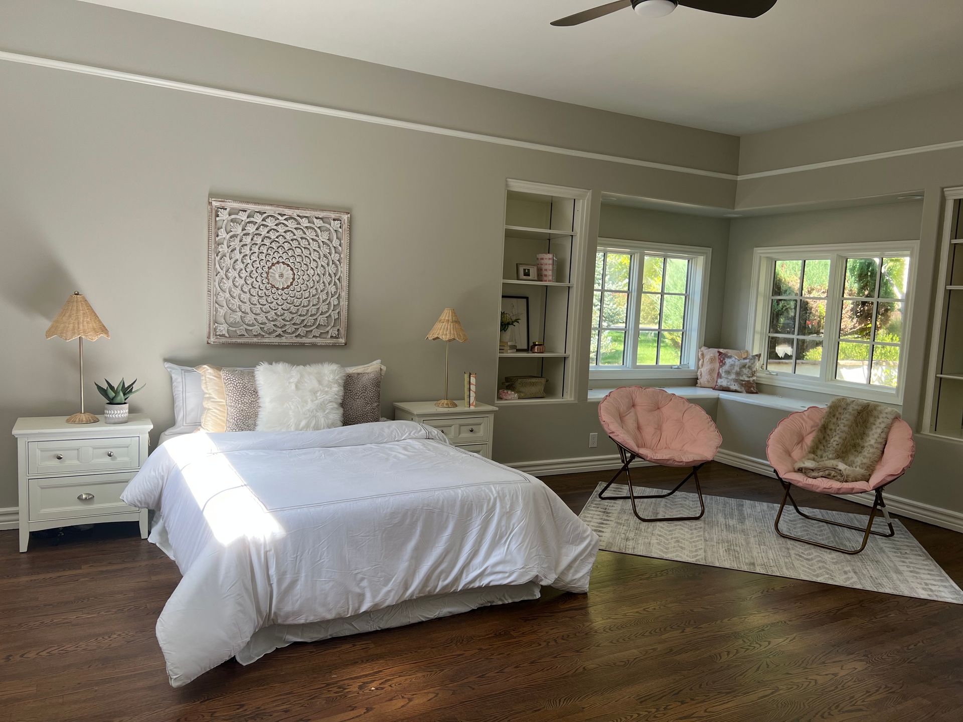 A bedroom with a bed , nightstand , chairs and a window.