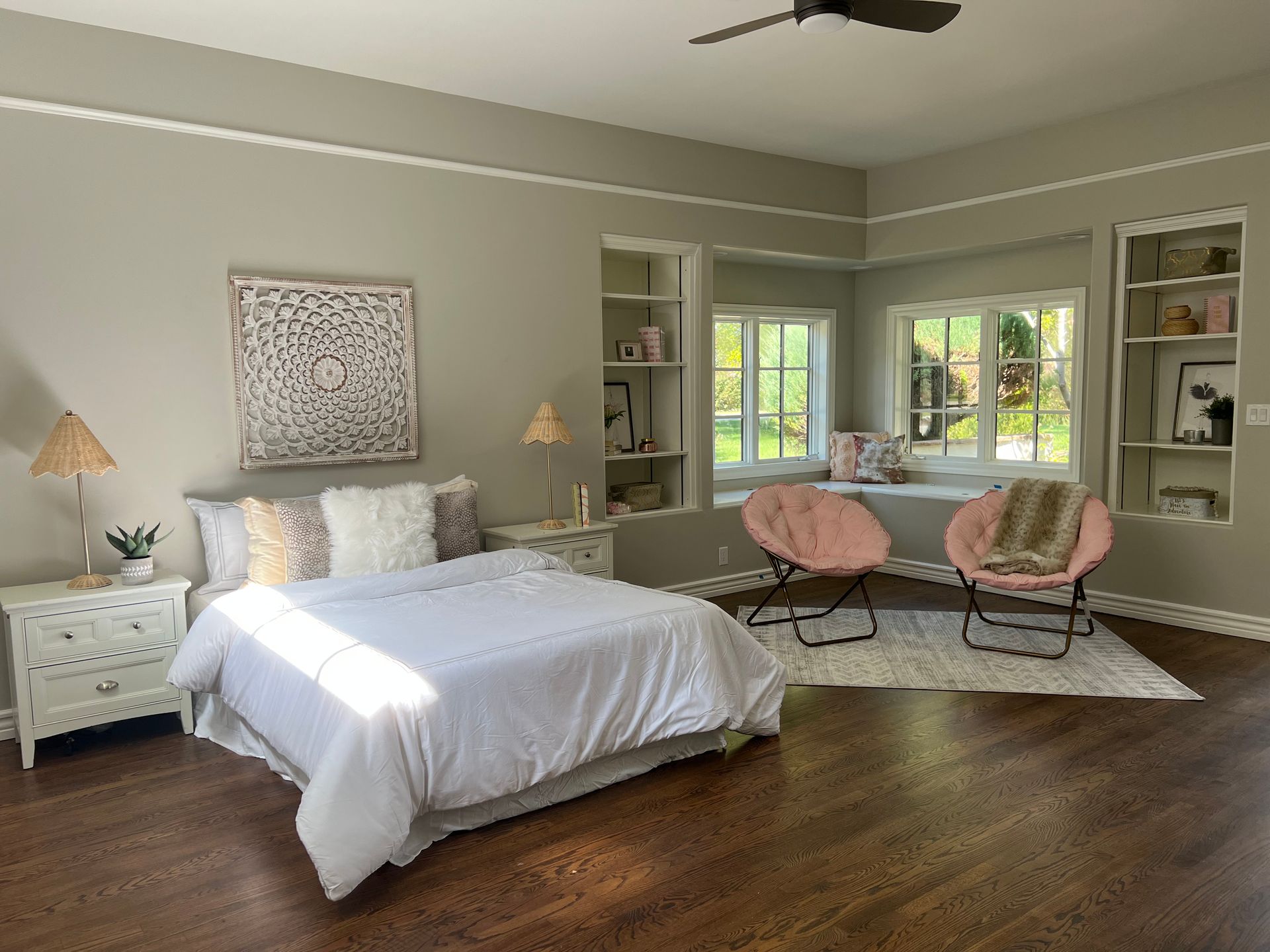 A bedroom with a bed , two chairs and a ceiling fan.
