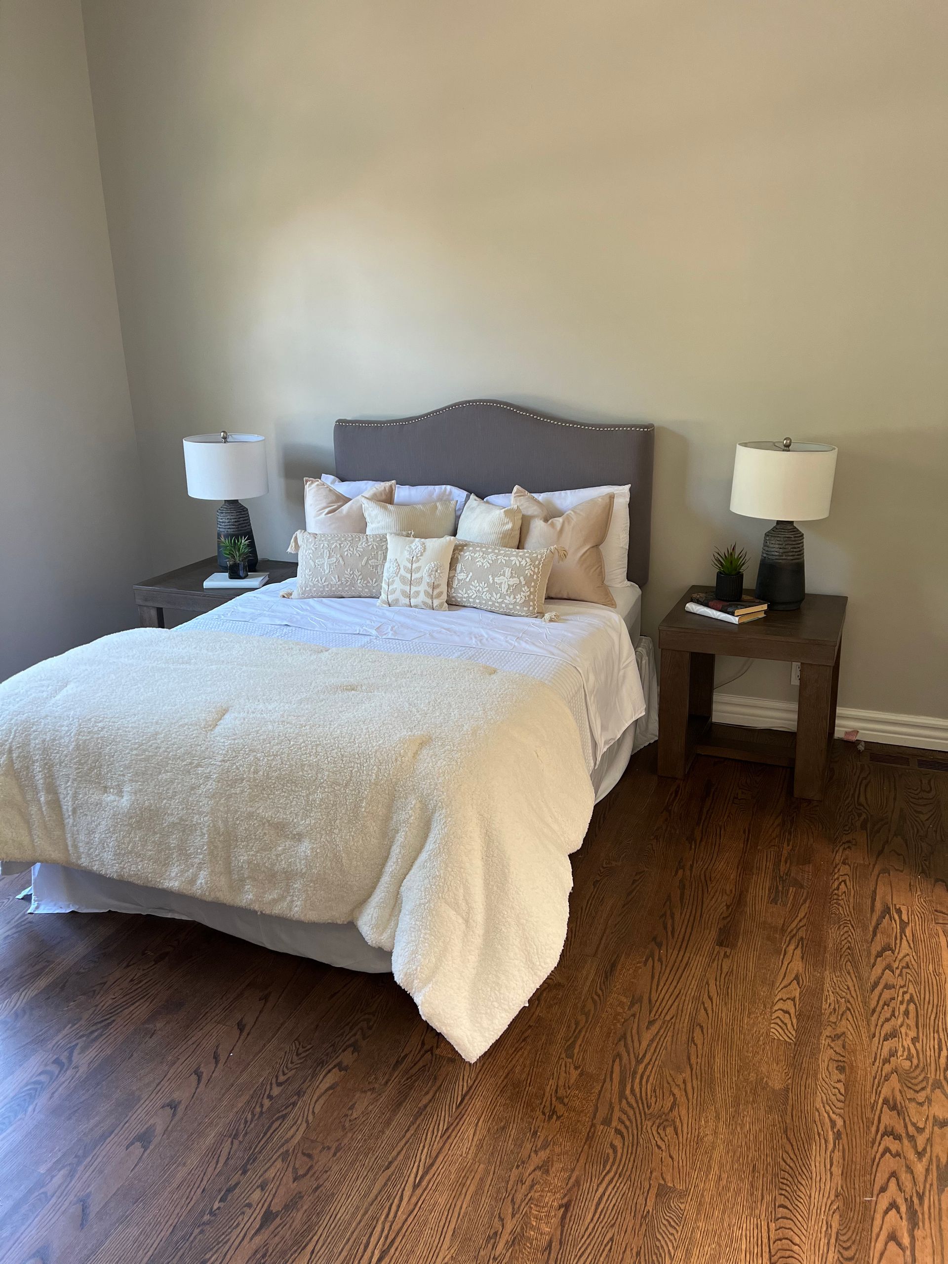 A bedroom with a bed , two lamps and a nightstand.