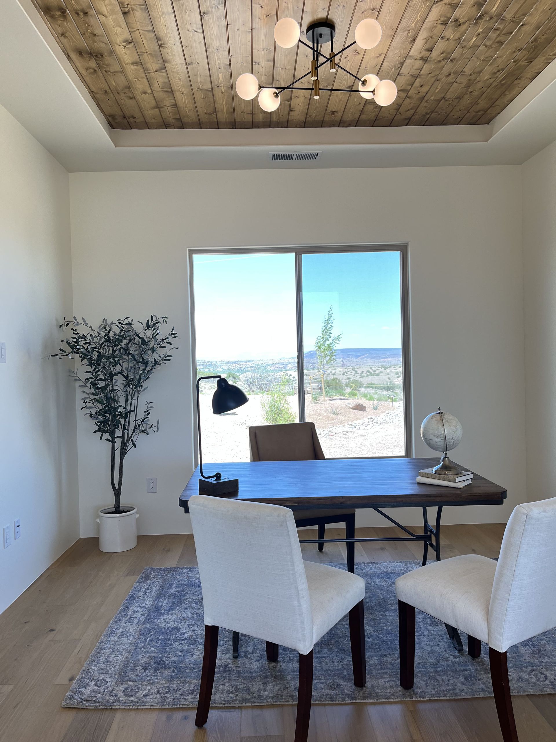A dining room with a table and chairs and a large window.