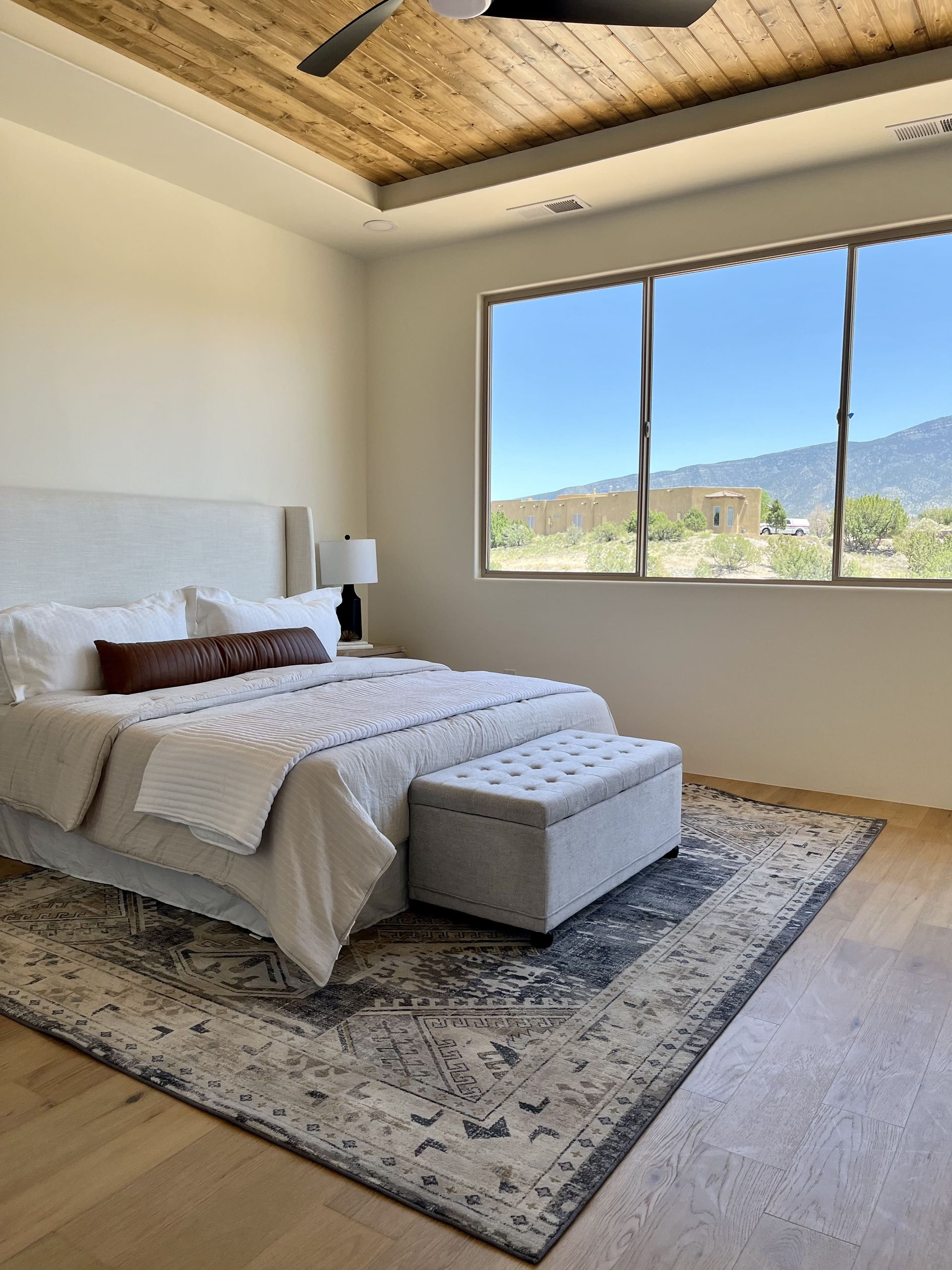 A bedroom with a king size bed , a rug , and a ceiling fan.