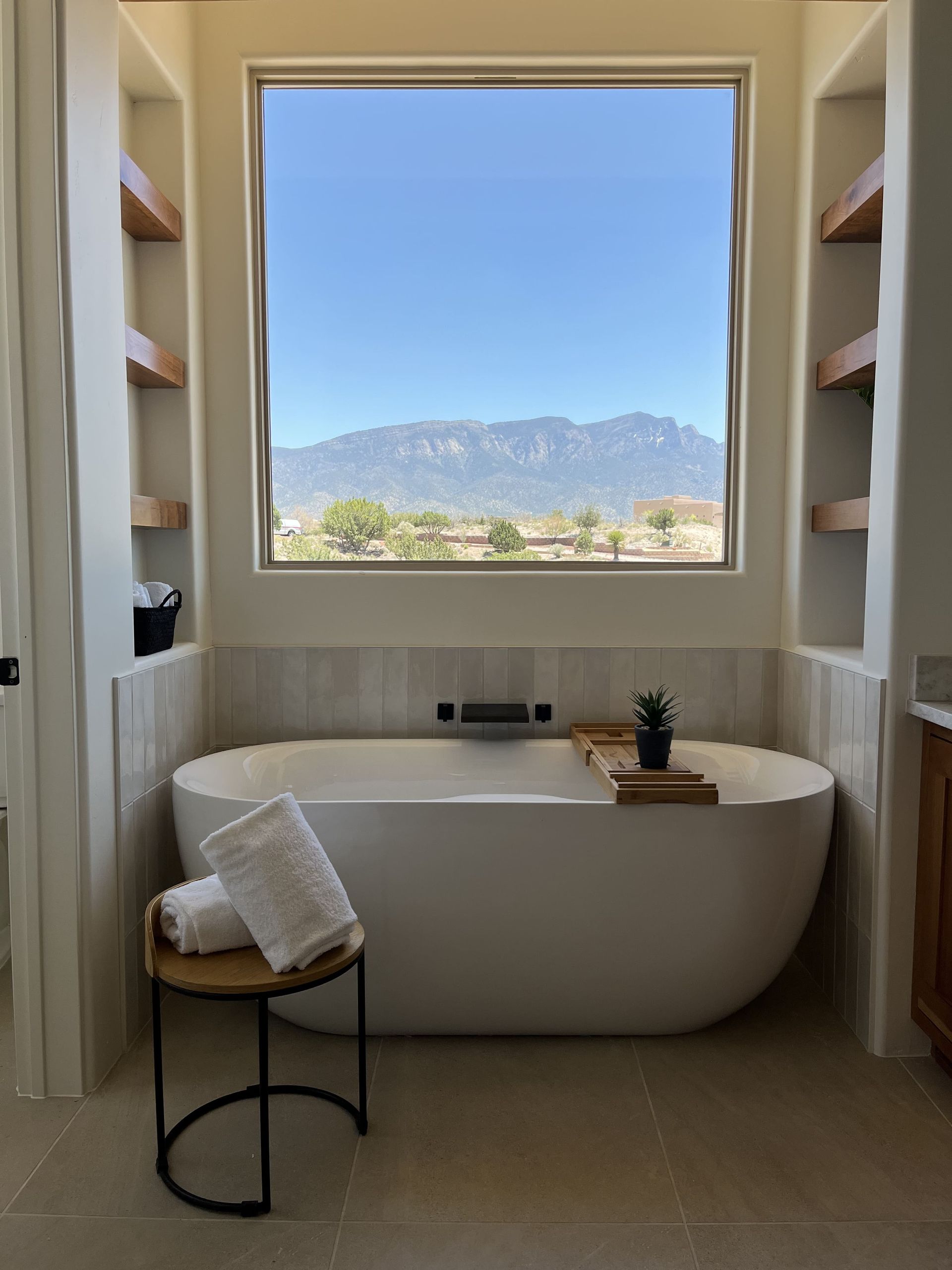 A bathroom with a tub and a window with mountains in the background
