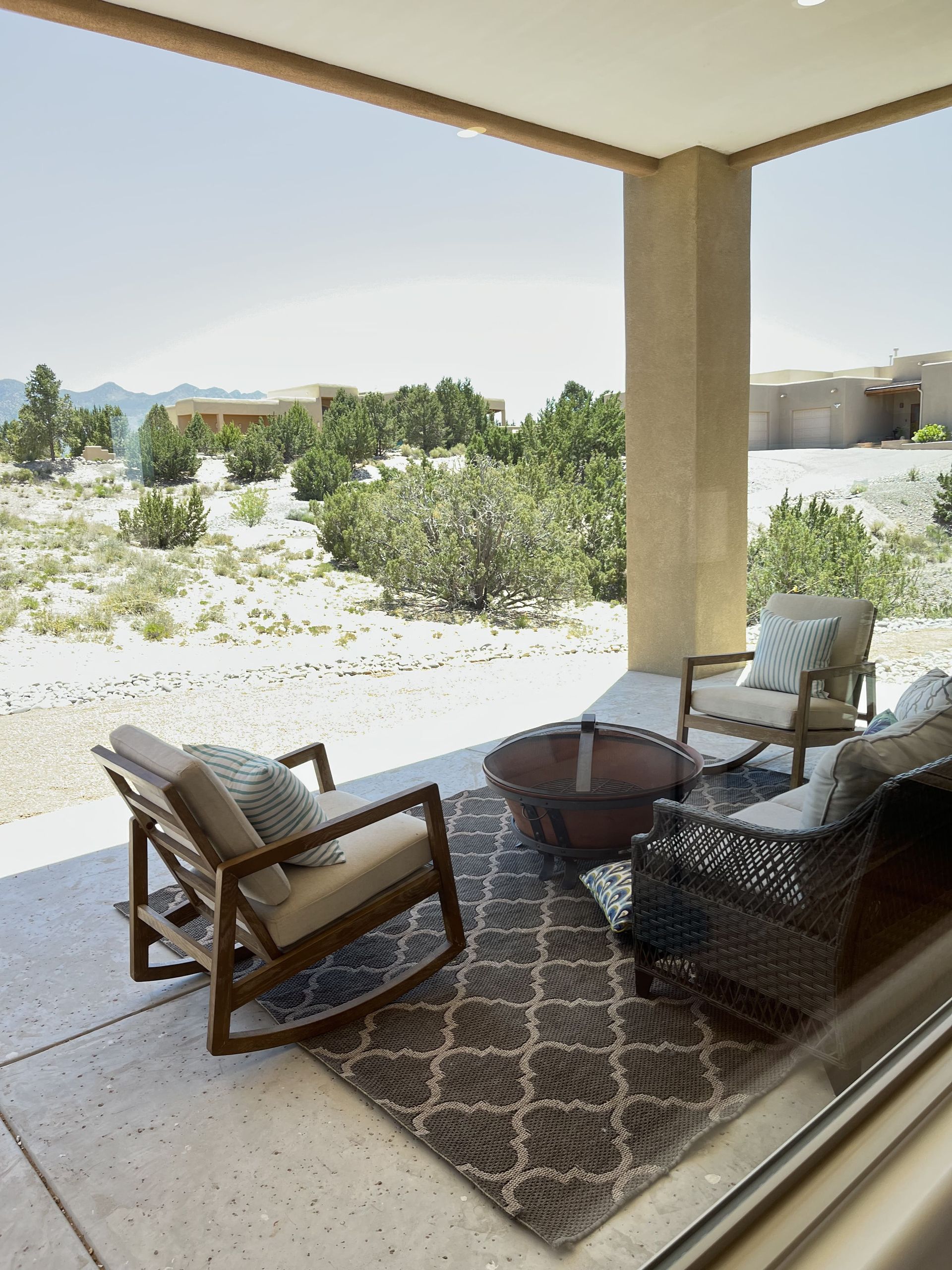 A patio with rocking chairs , a table and a rug