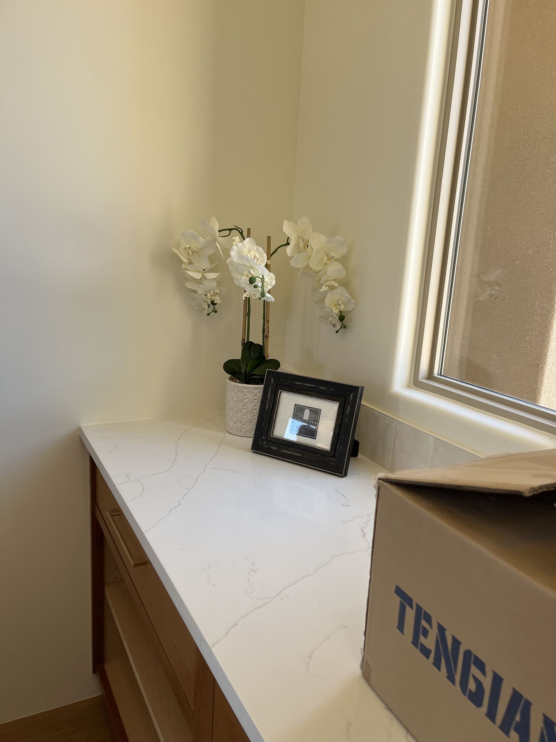 A picture frame is sitting on a counter next to a window.