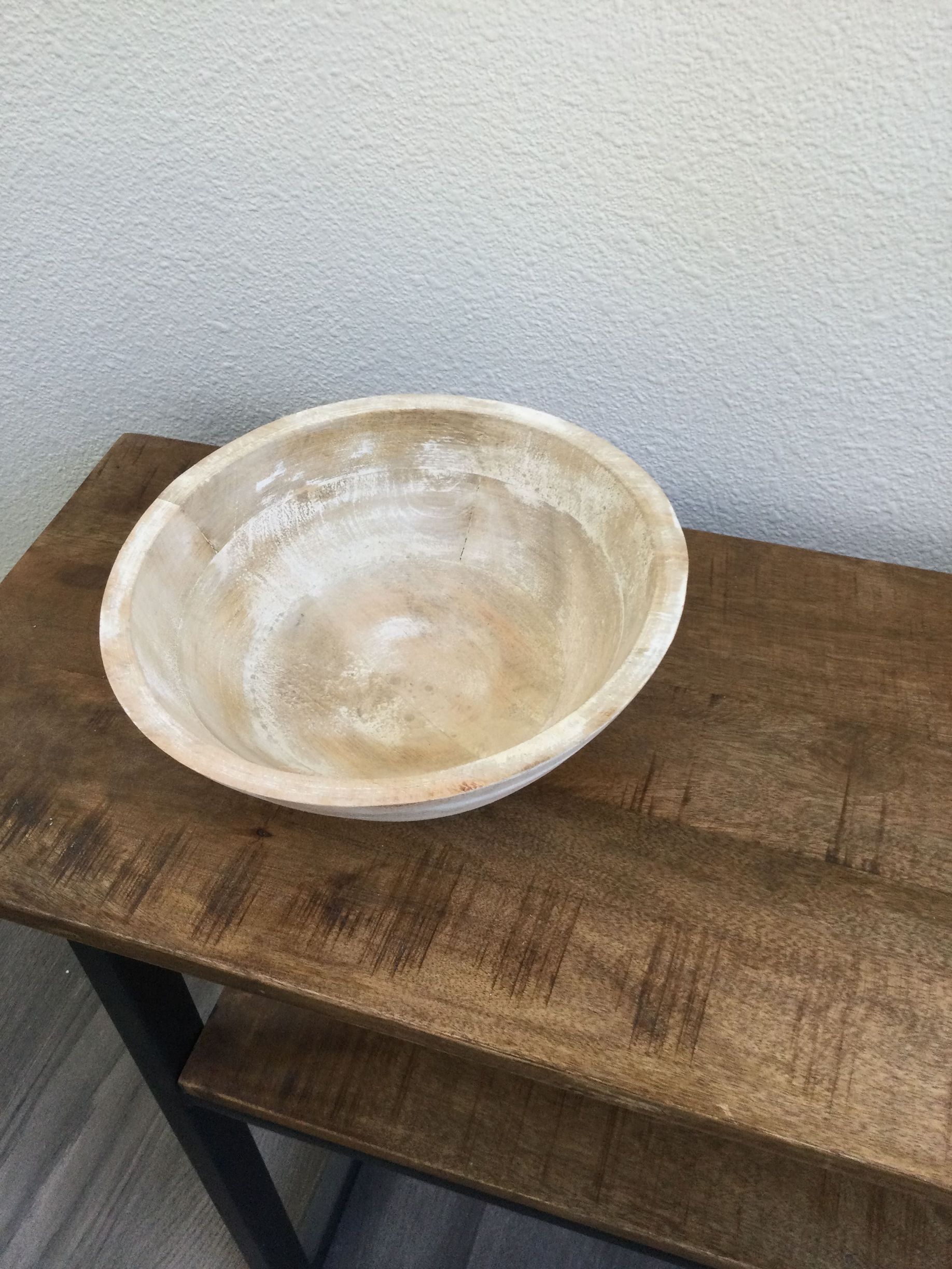 A wooden bowl is sitting on top of a wooden table.