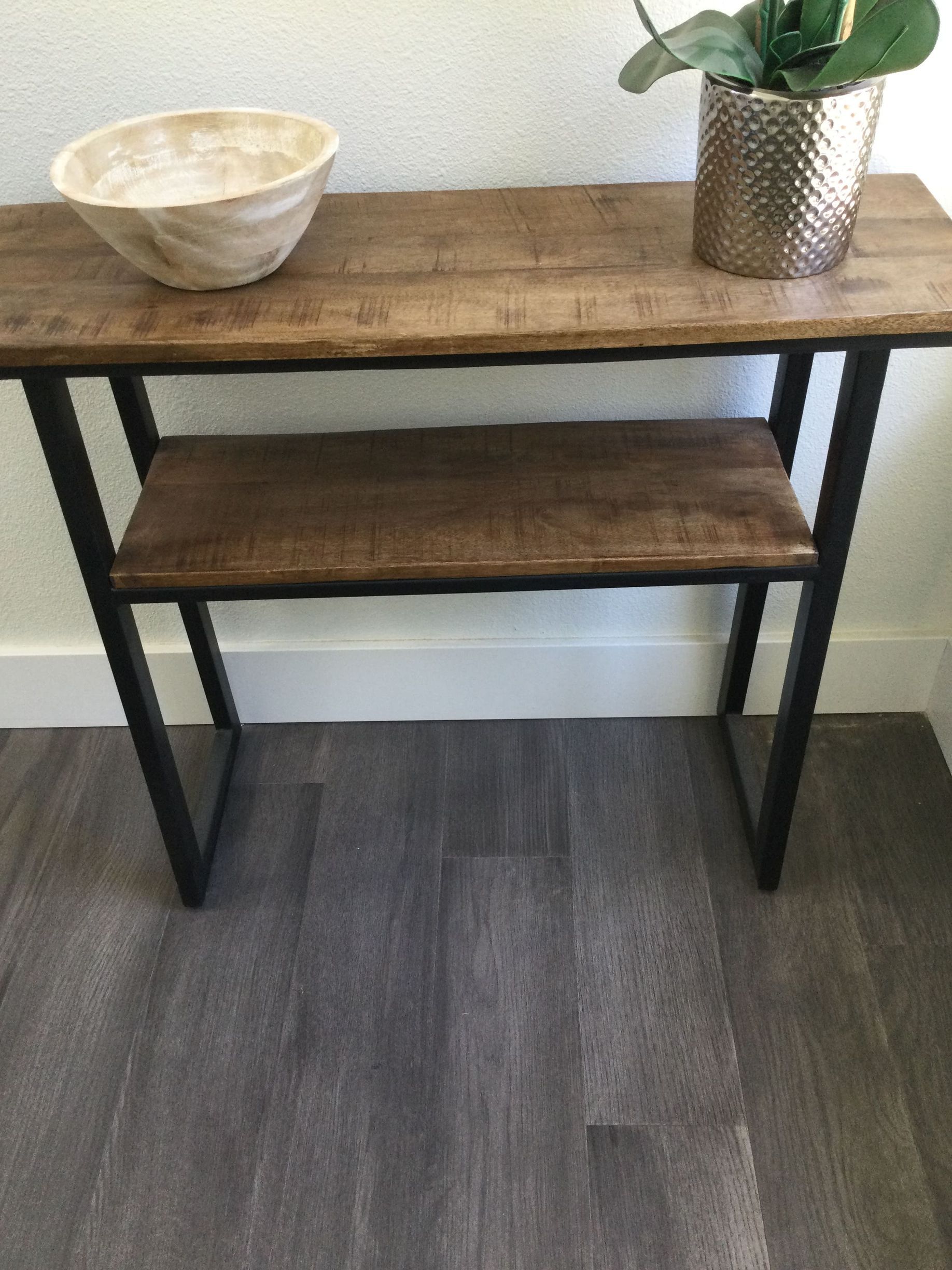 A wooden table with a bowl and a plant on it.