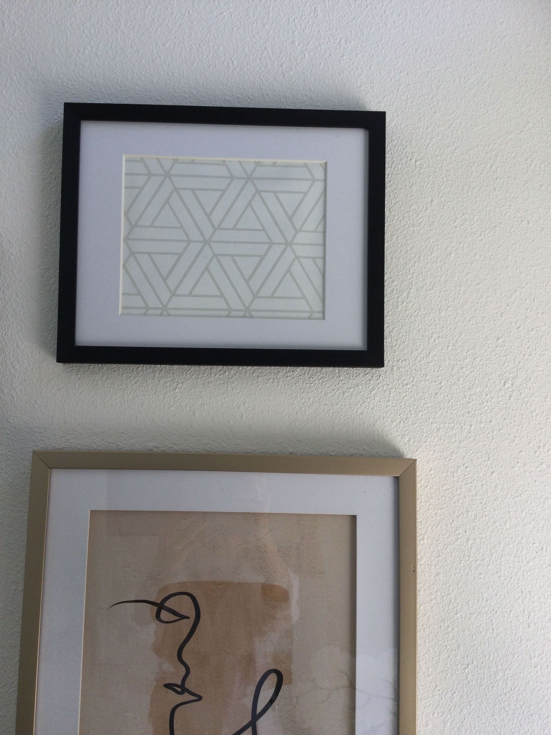 Two framed pictures are hanging on a white wall.