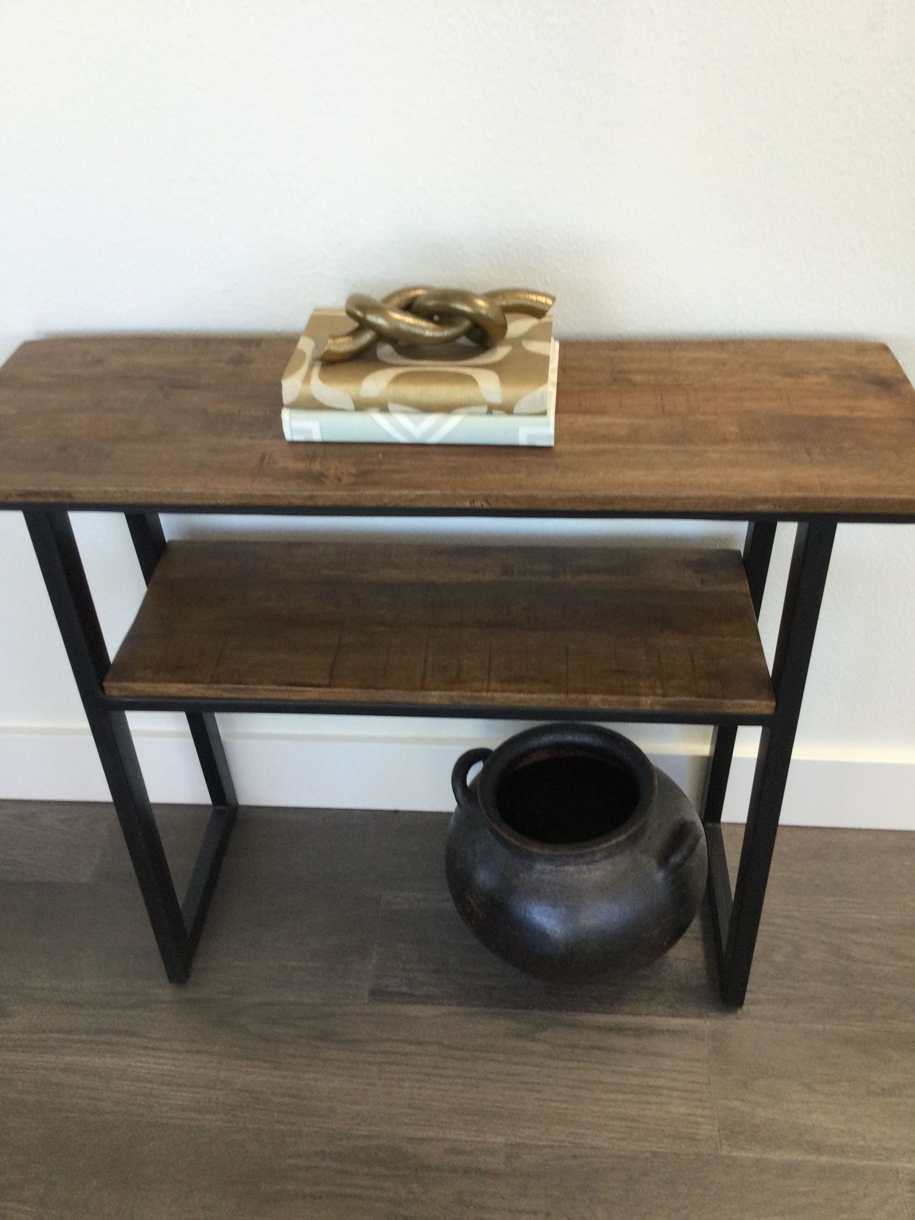 A wooden table with a book and a vase on it