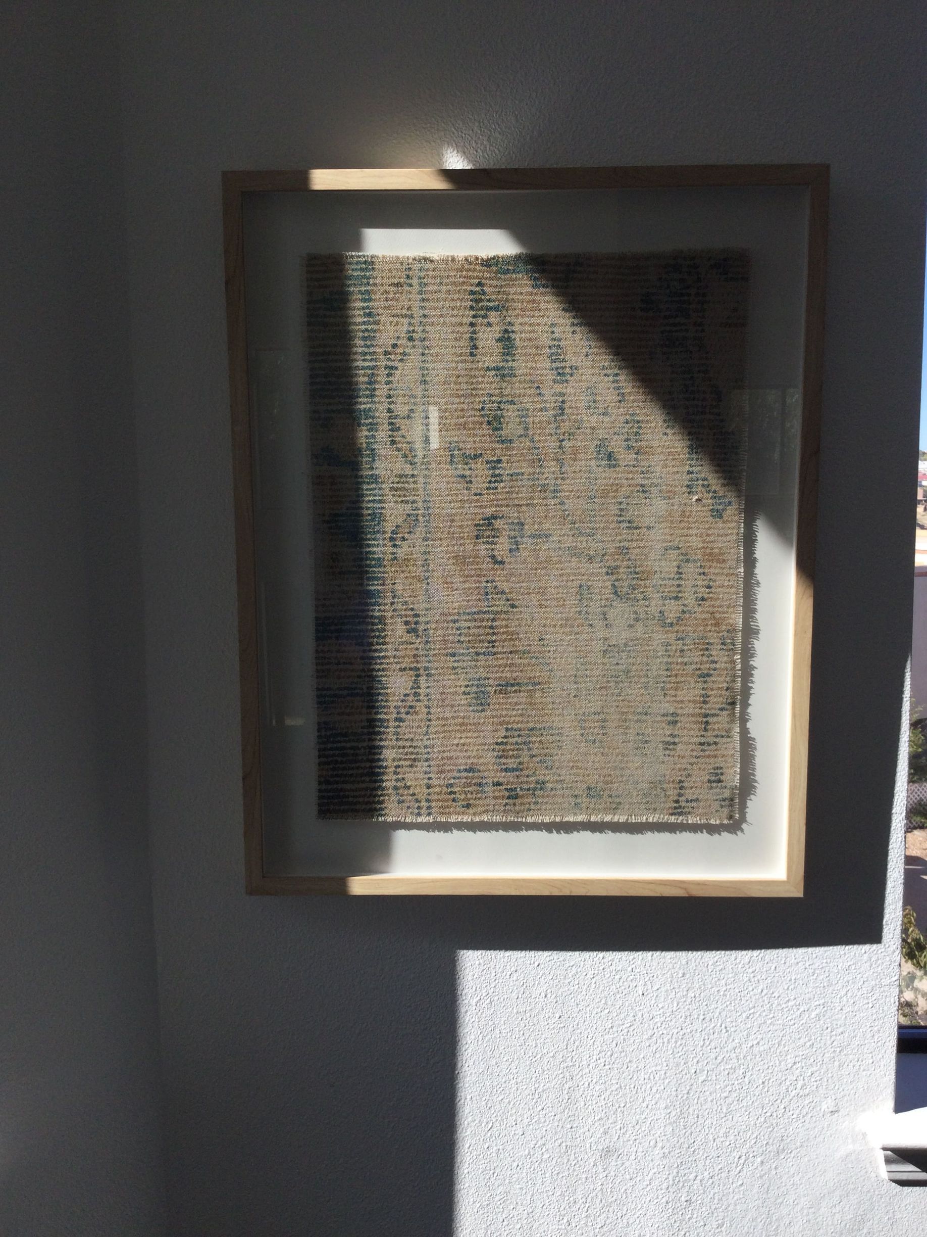 A picture in a wooden frame is hanging on a wall.