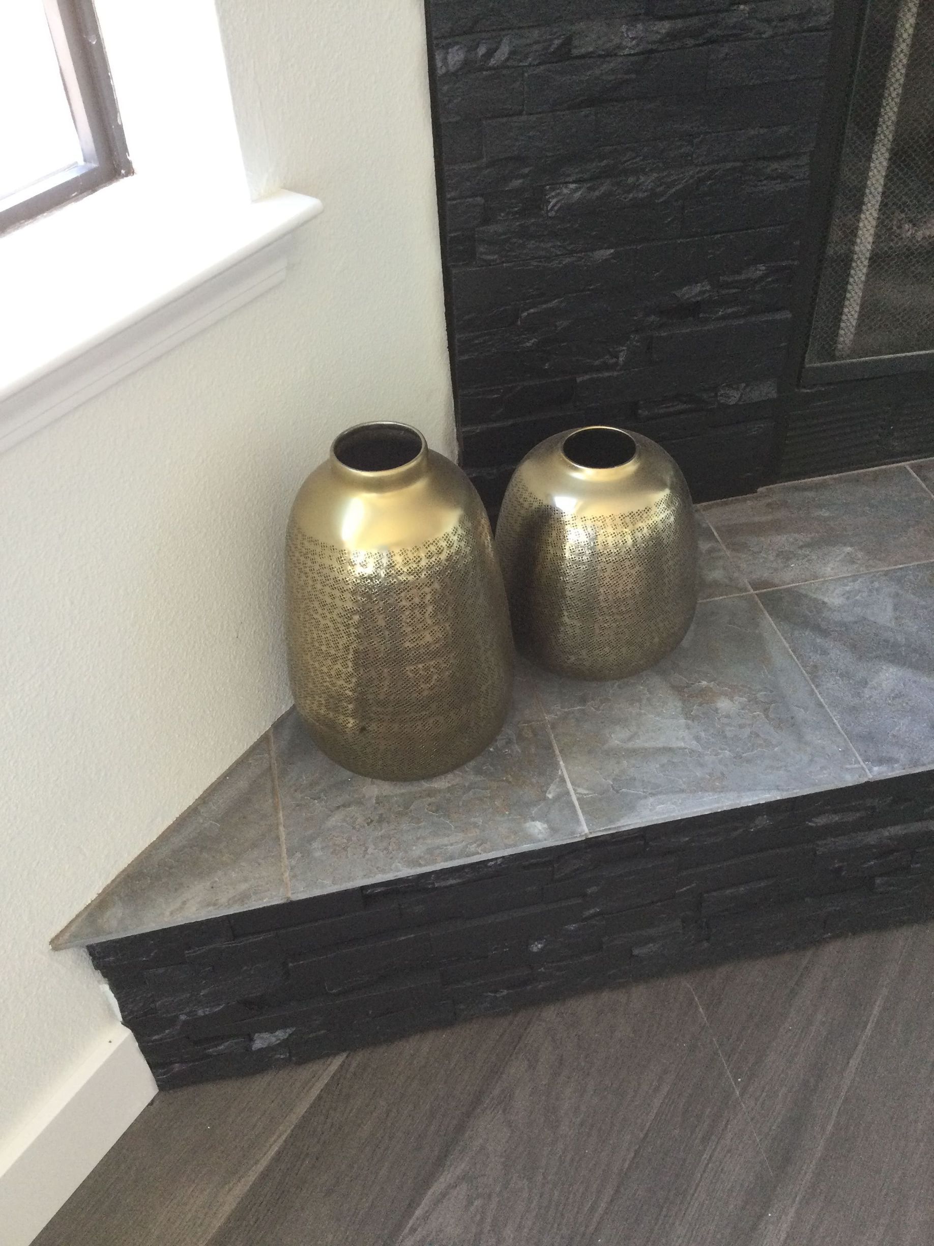 Two vases are sitting on a corner of a fireplace.