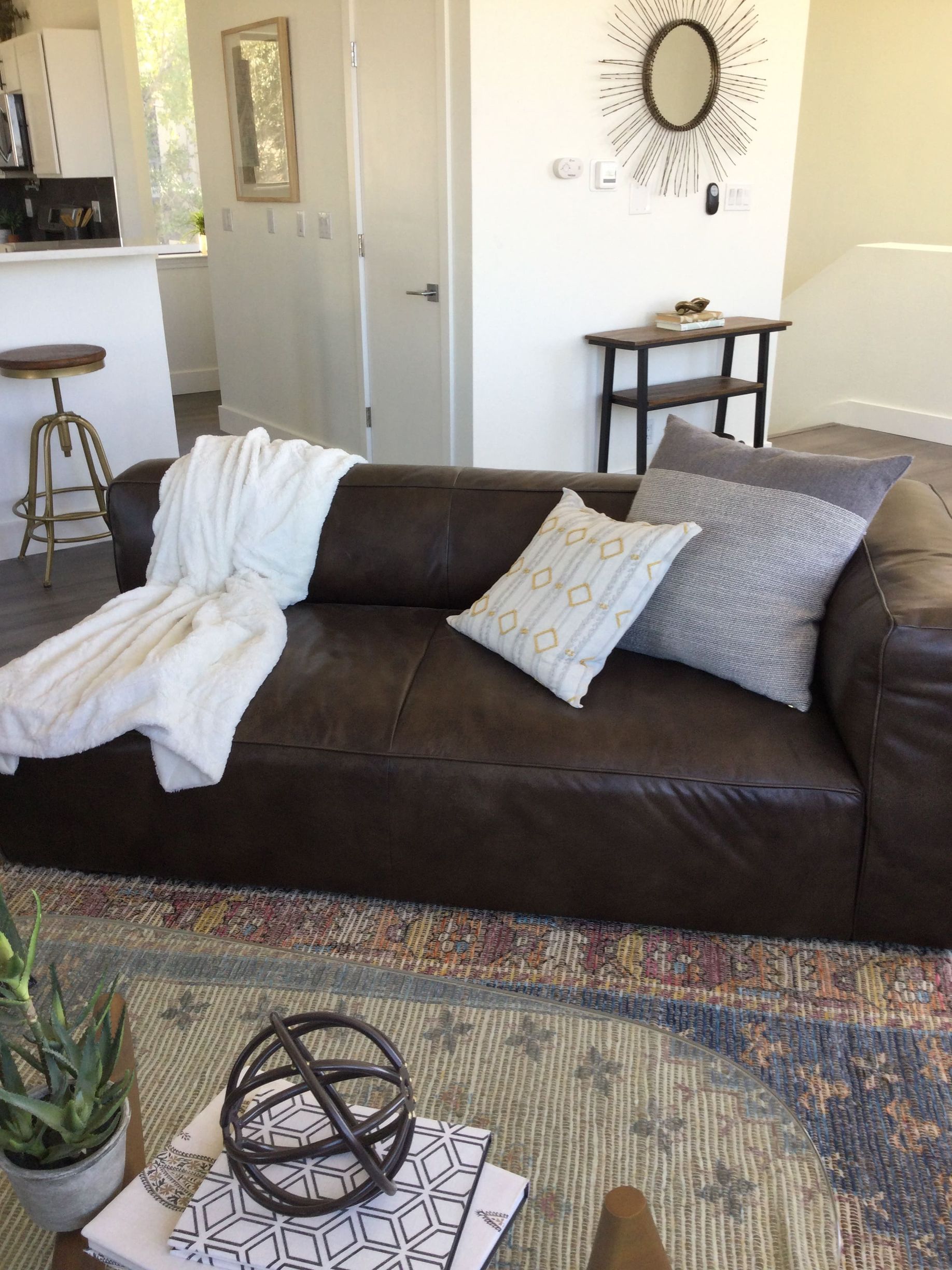 A living room with a brown leather couch and pillows