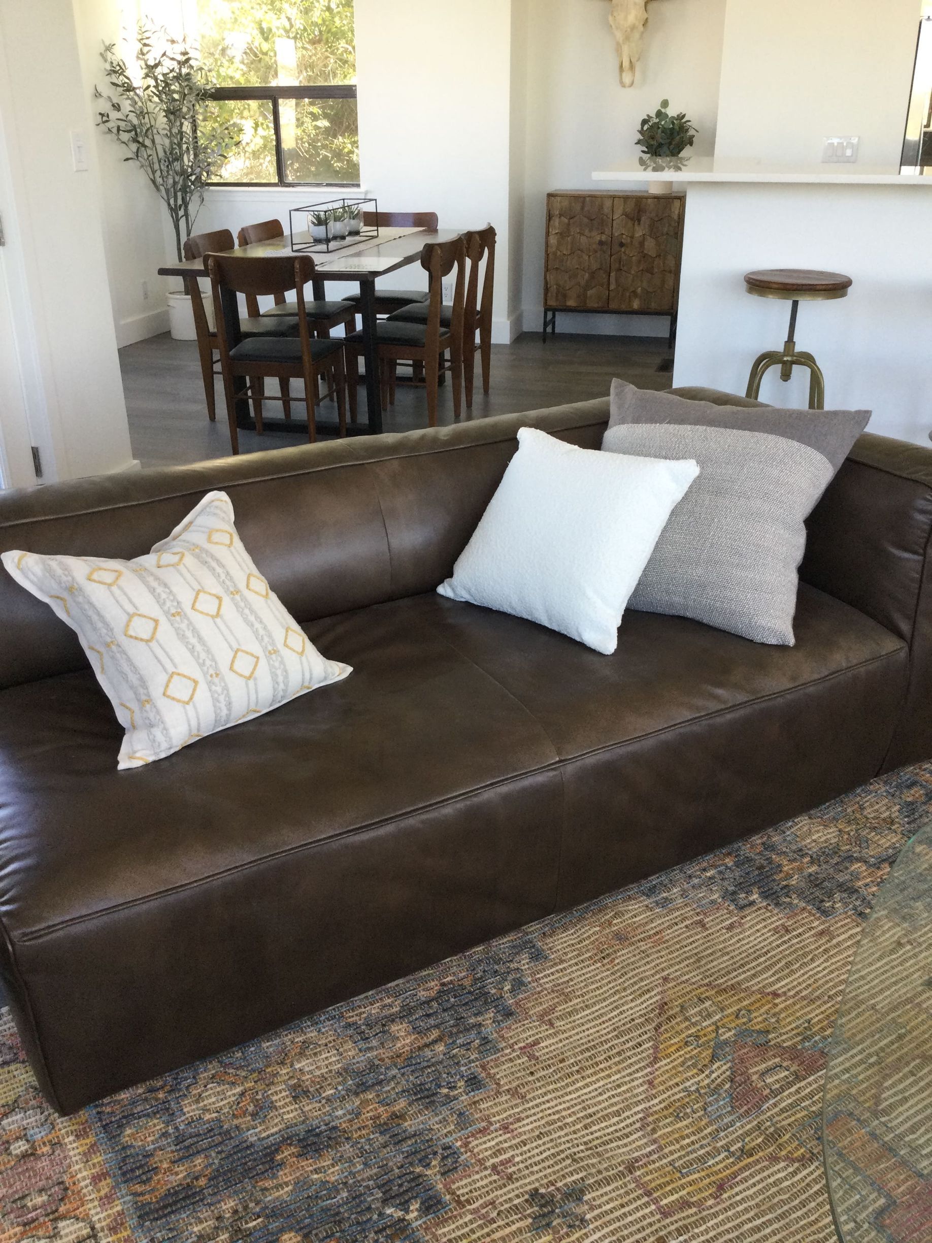 A brown leather couch with white pillows in a living room.