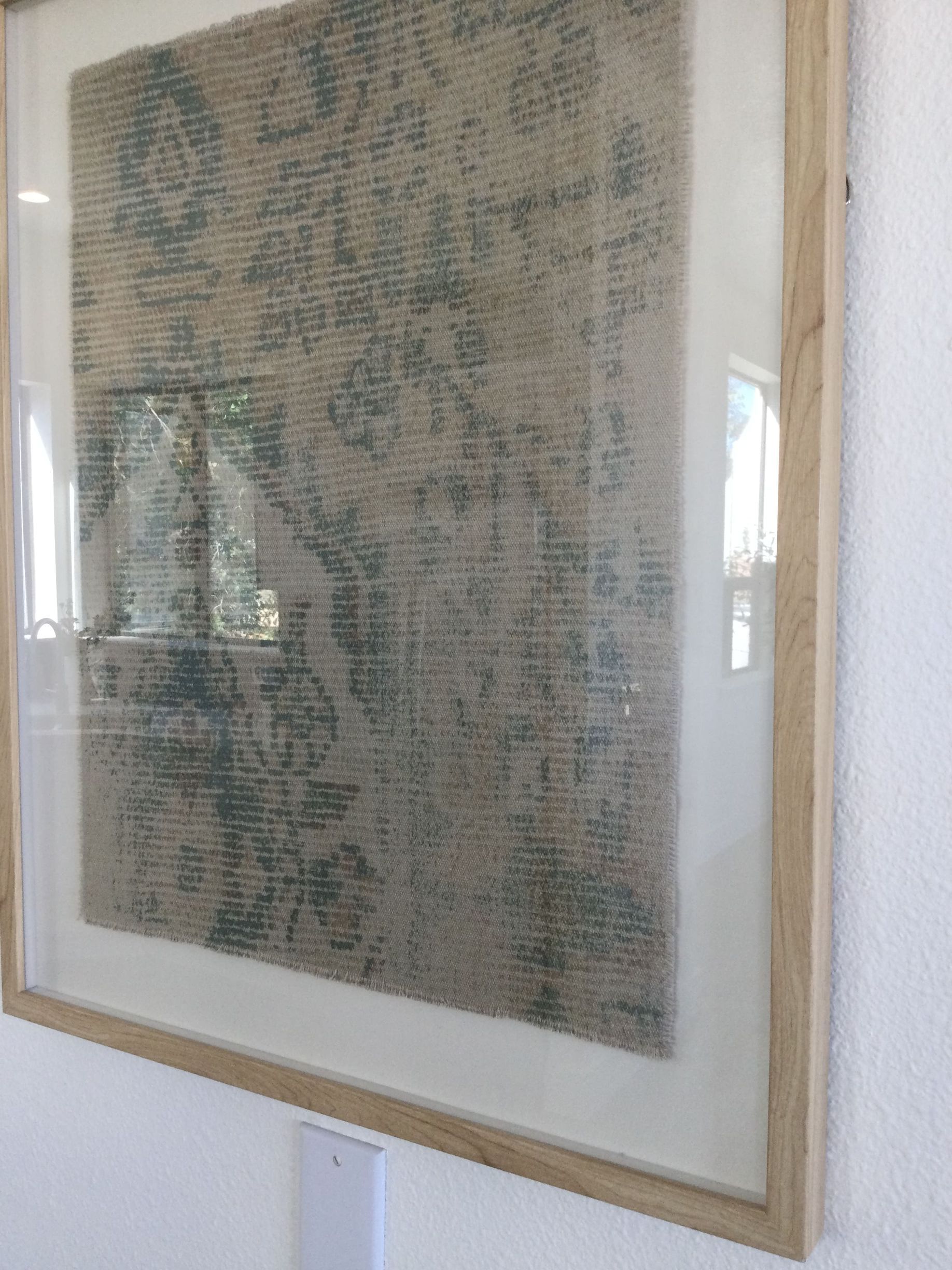 A framed picture is hanging on a white wall.