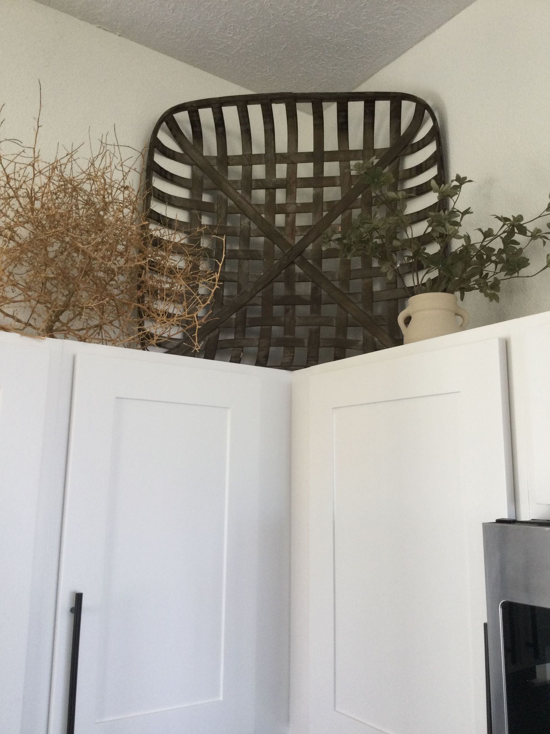 A kitchen with white cabinets and a basket hanging on the wall.