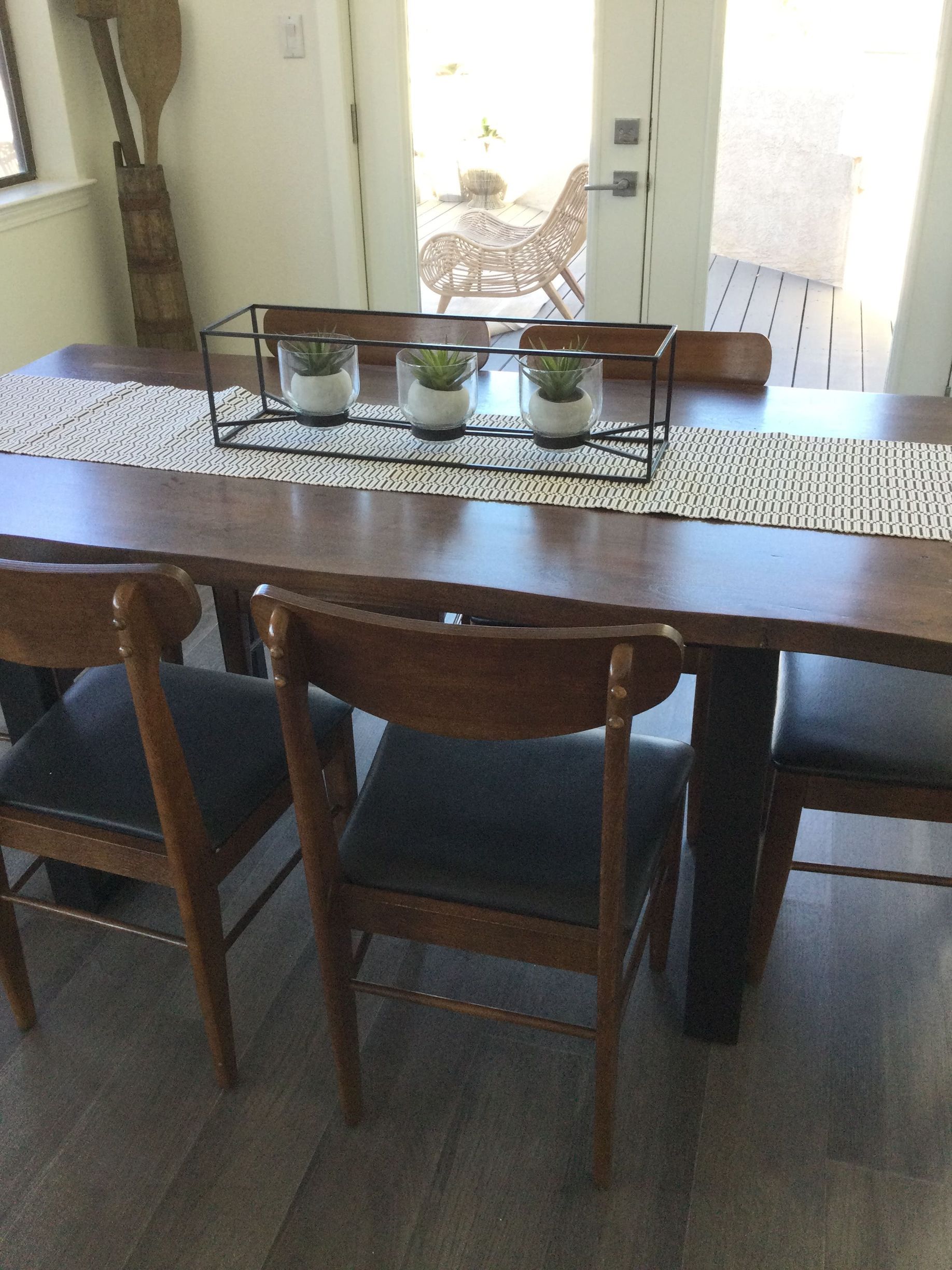 A dining room table with chairs and potted plants on it