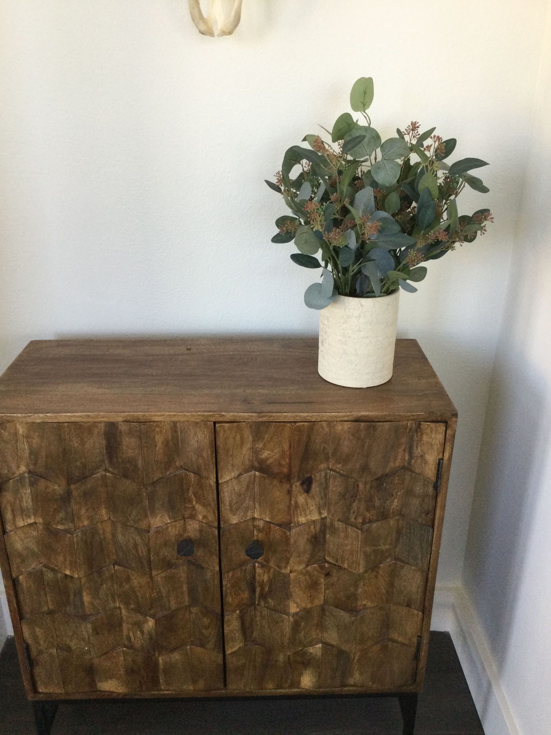 A potted plant is sitting on top of a wooden cabinet.
