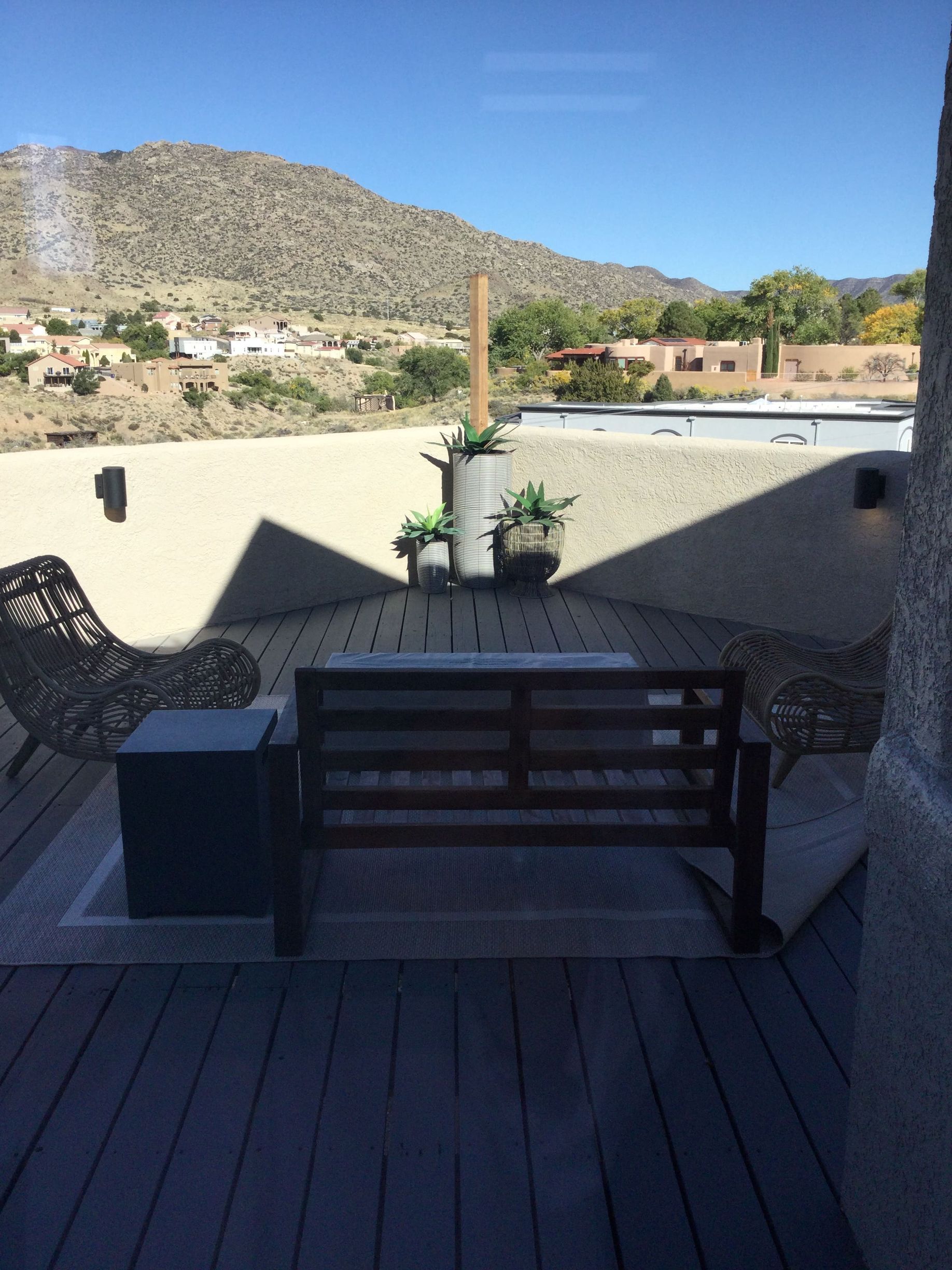 A deck with a rocking bench and chairs with mountains in the background