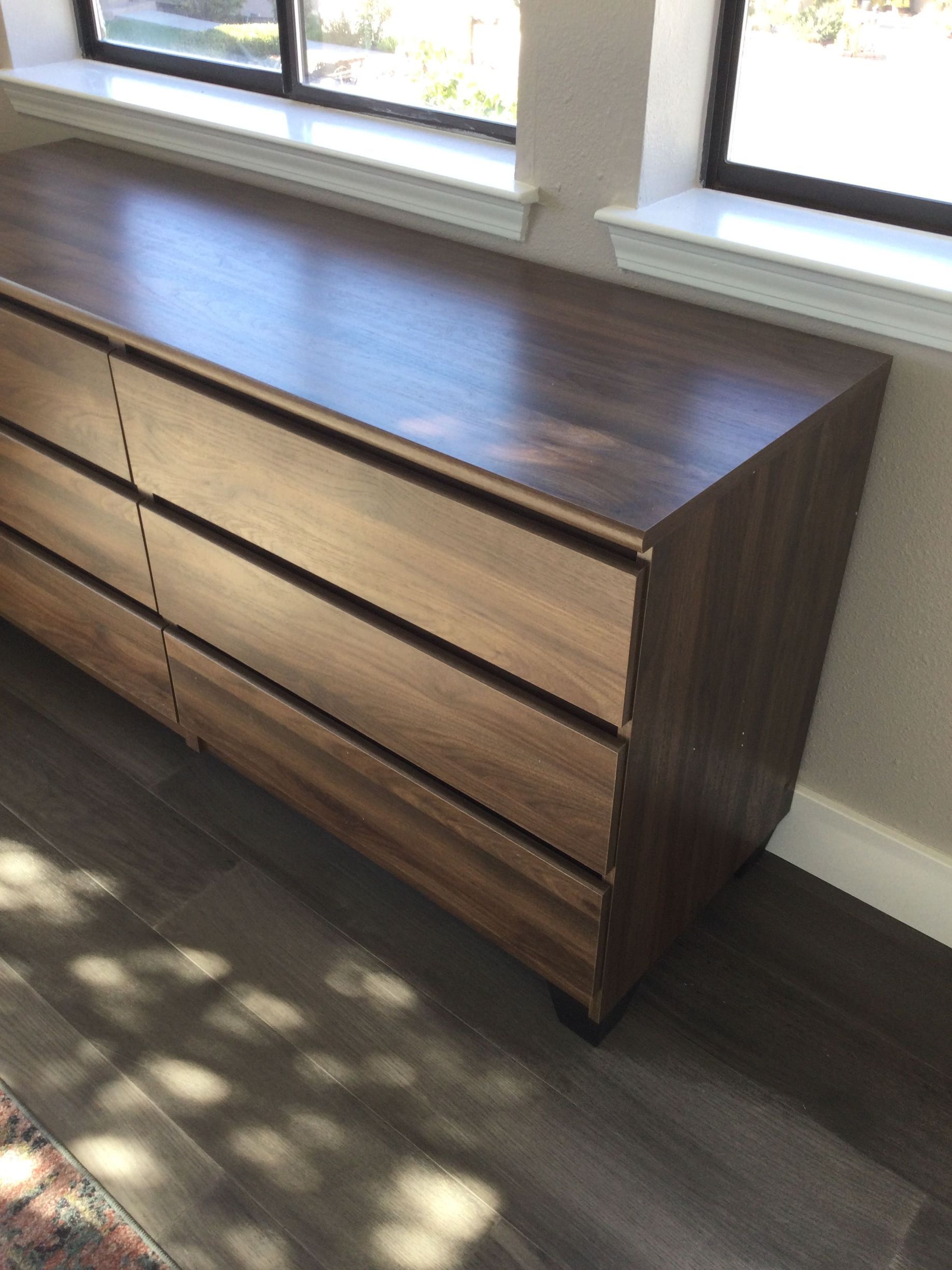 A wooden dresser is sitting in front of a window
