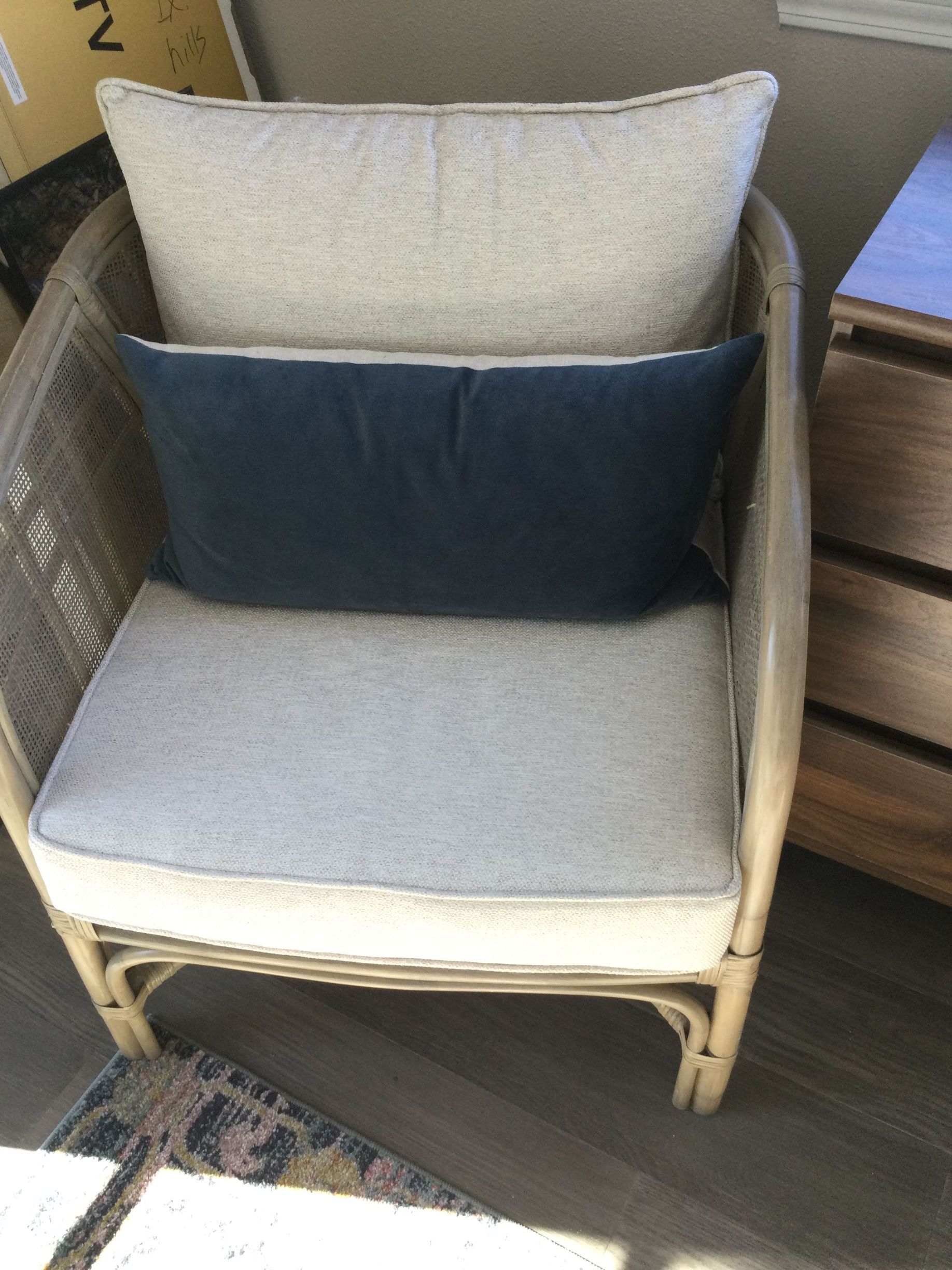 A wicker chair with two pillows on it in a room.