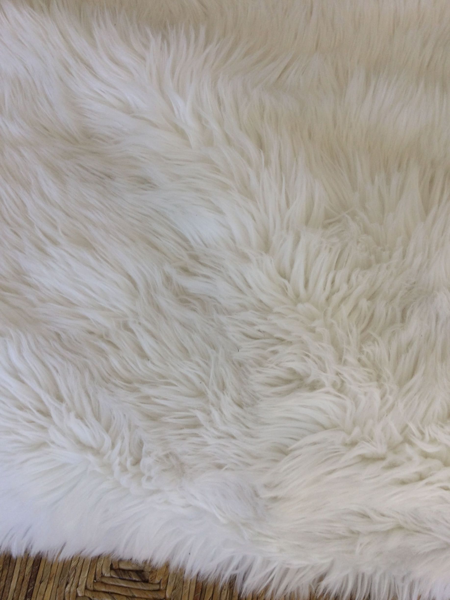 A close up of a white fur rug on a chair.