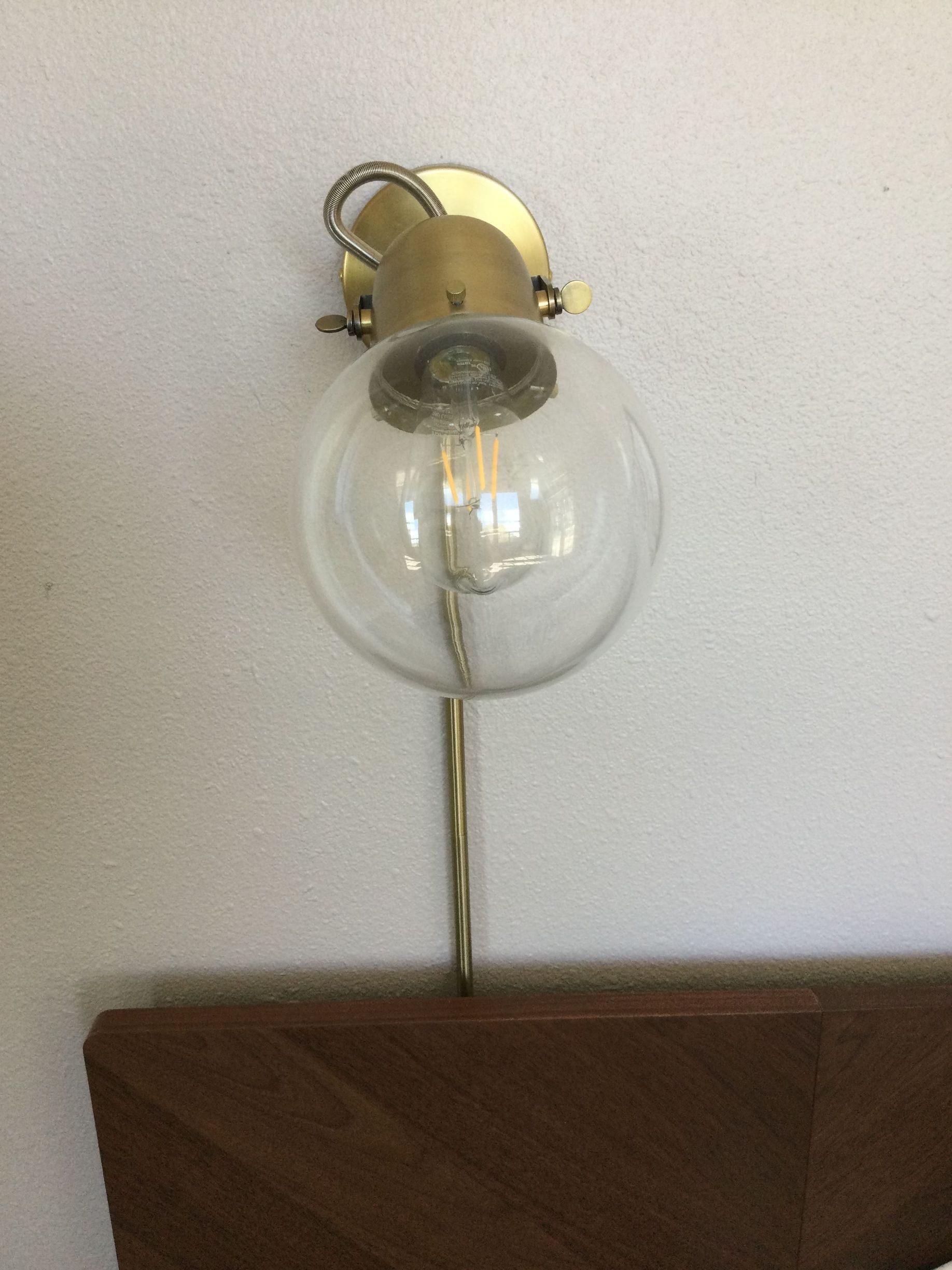 A brass wall light with a clear glass globe