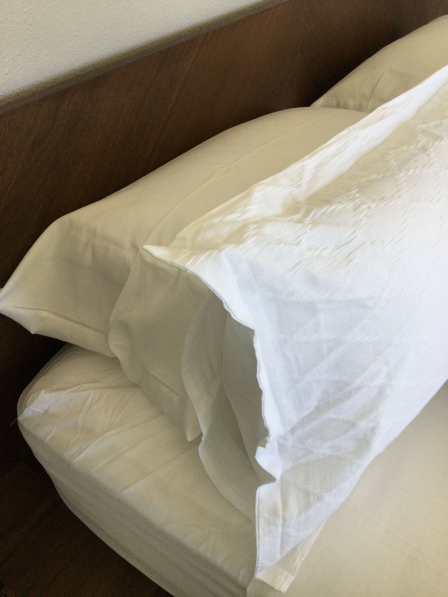 A bed with two white pillows and a brown headboard