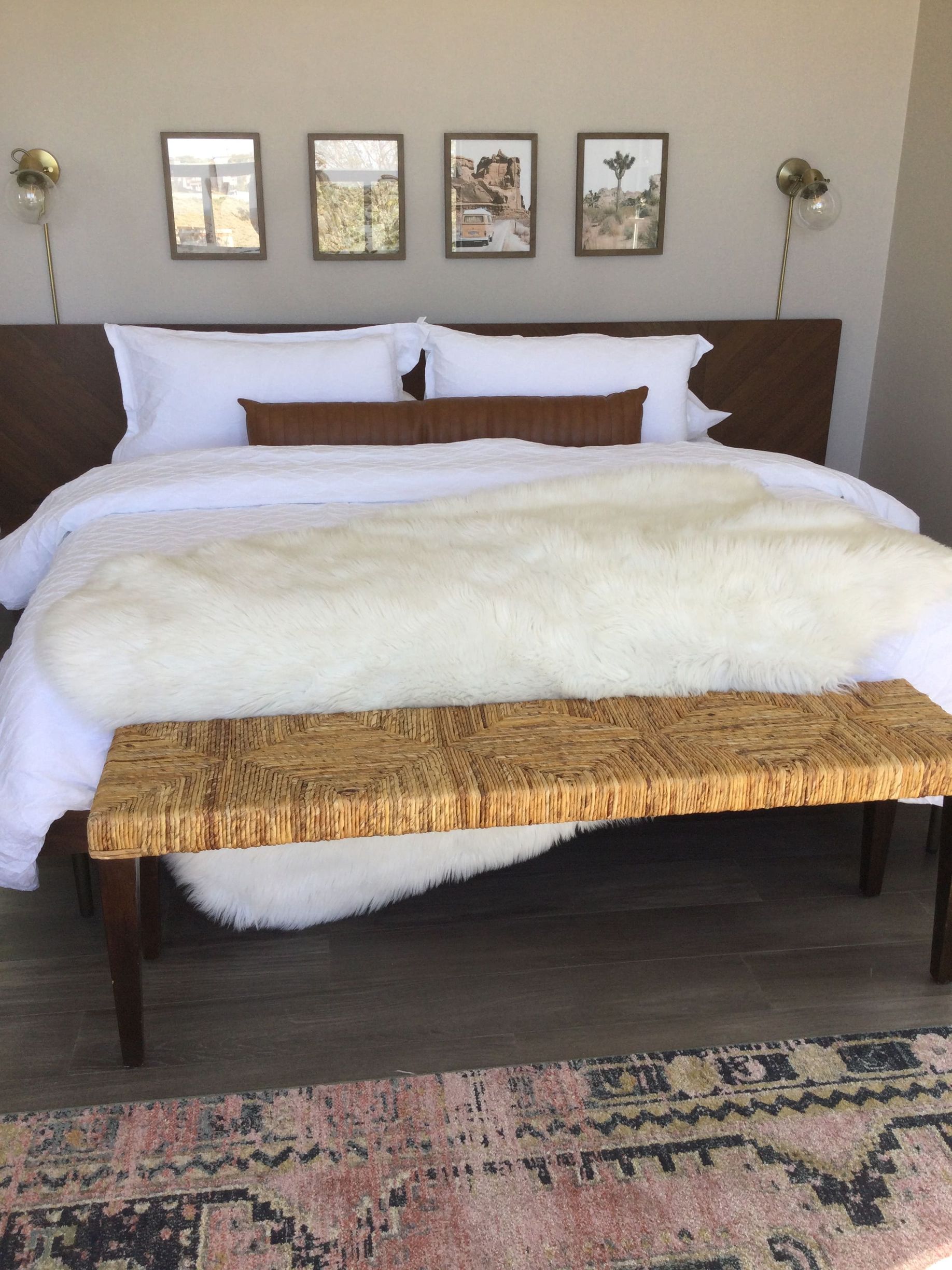A bed with white sheets and a bench in front of it