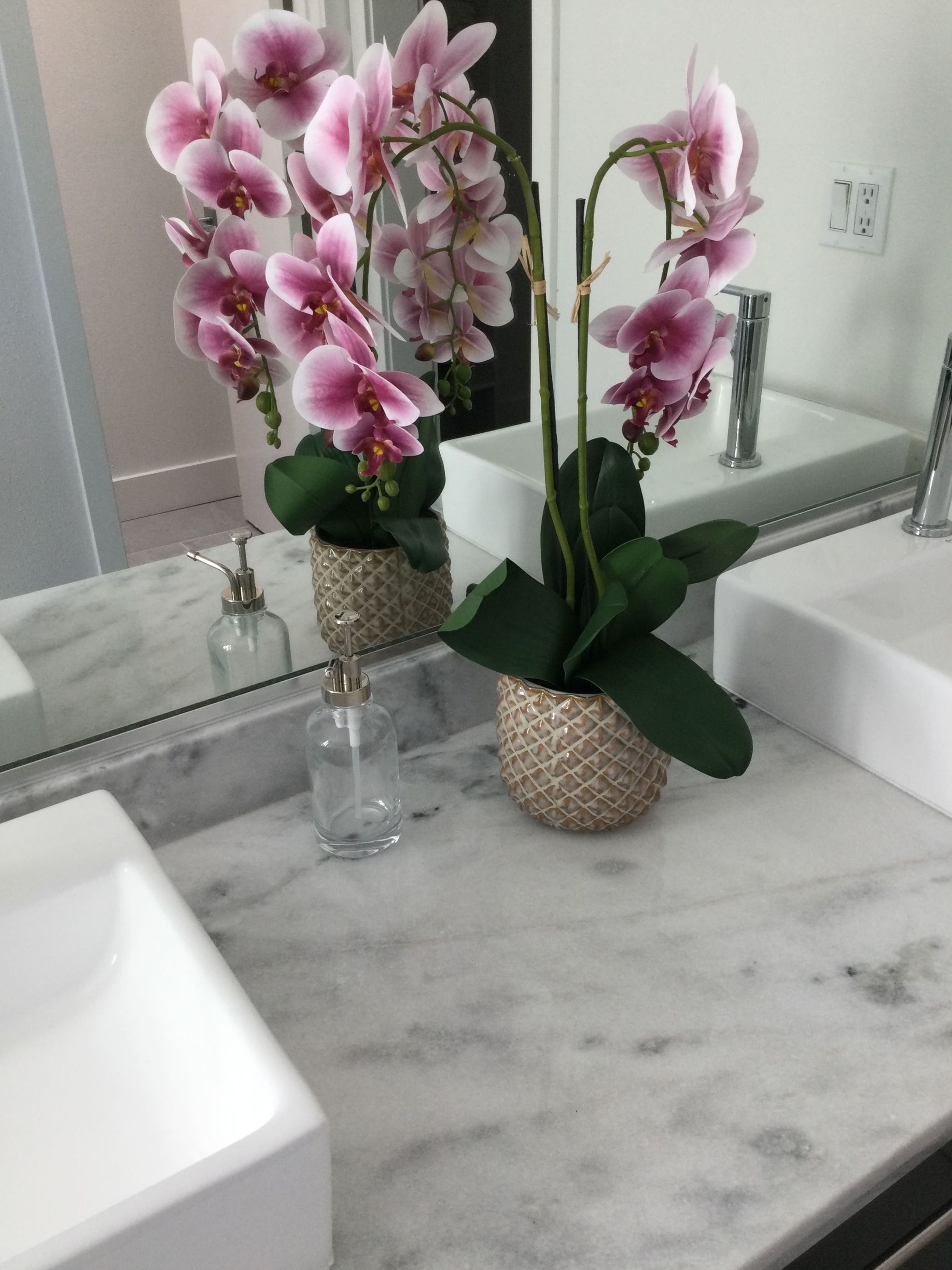 A bathroom sink with a vase of pink flowers on it
