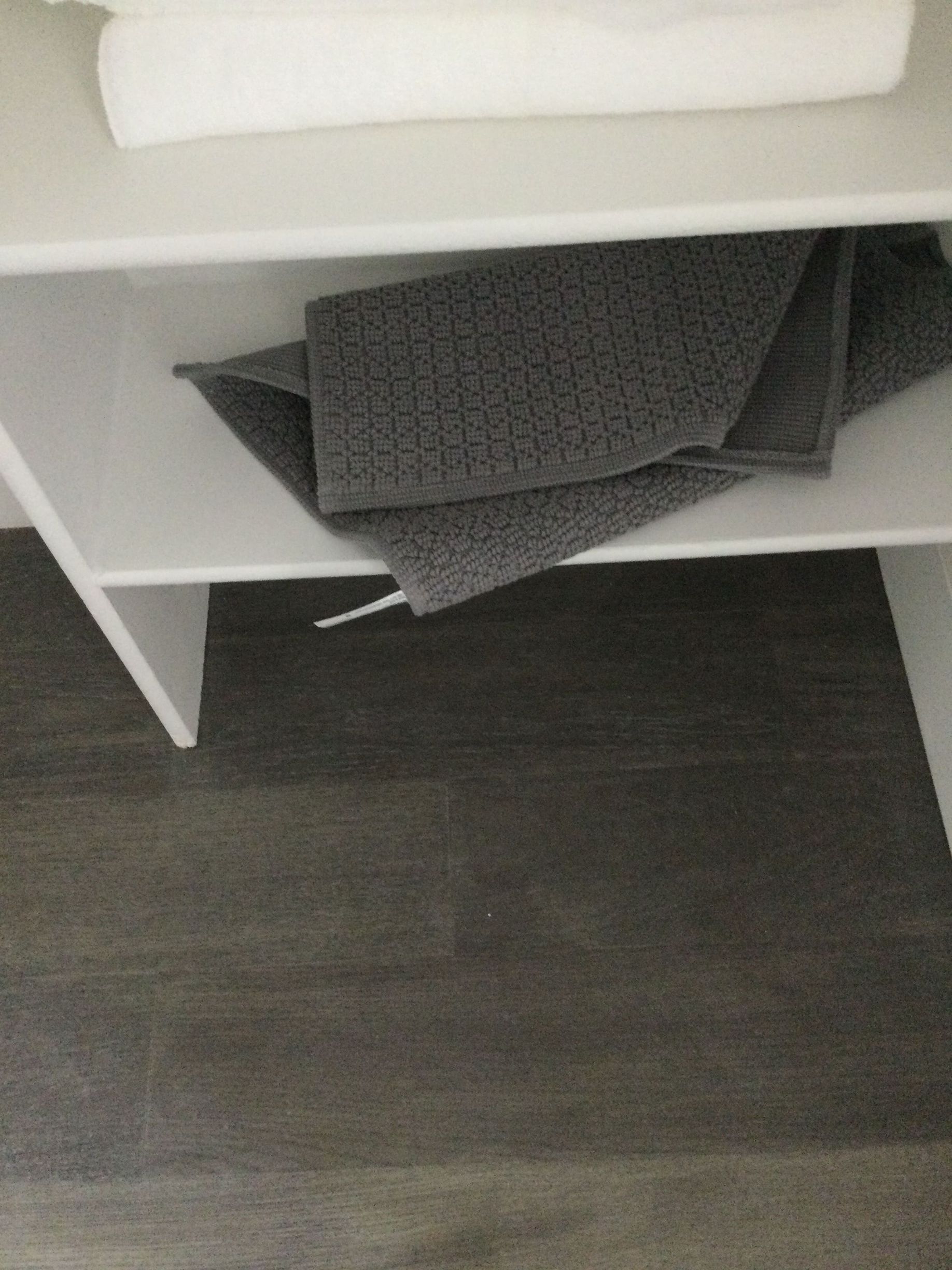A shelf with towels and a rug on it