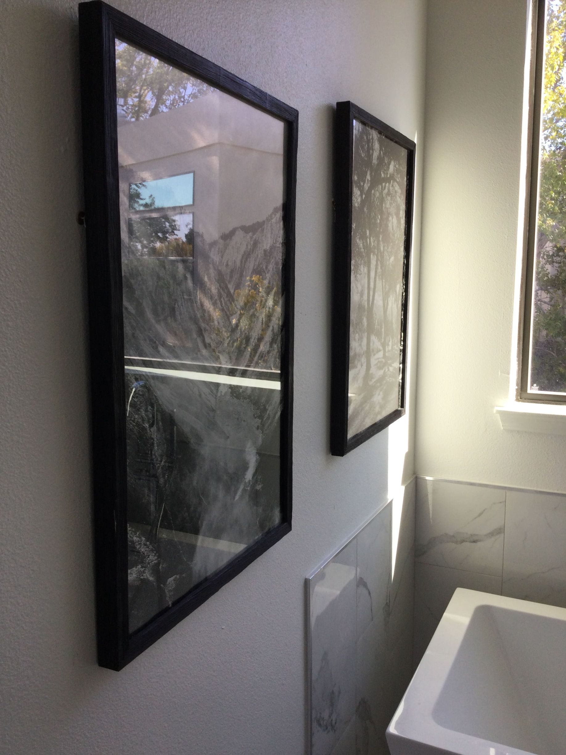Two framed pictures are hanging on a wall next to a bathtub.