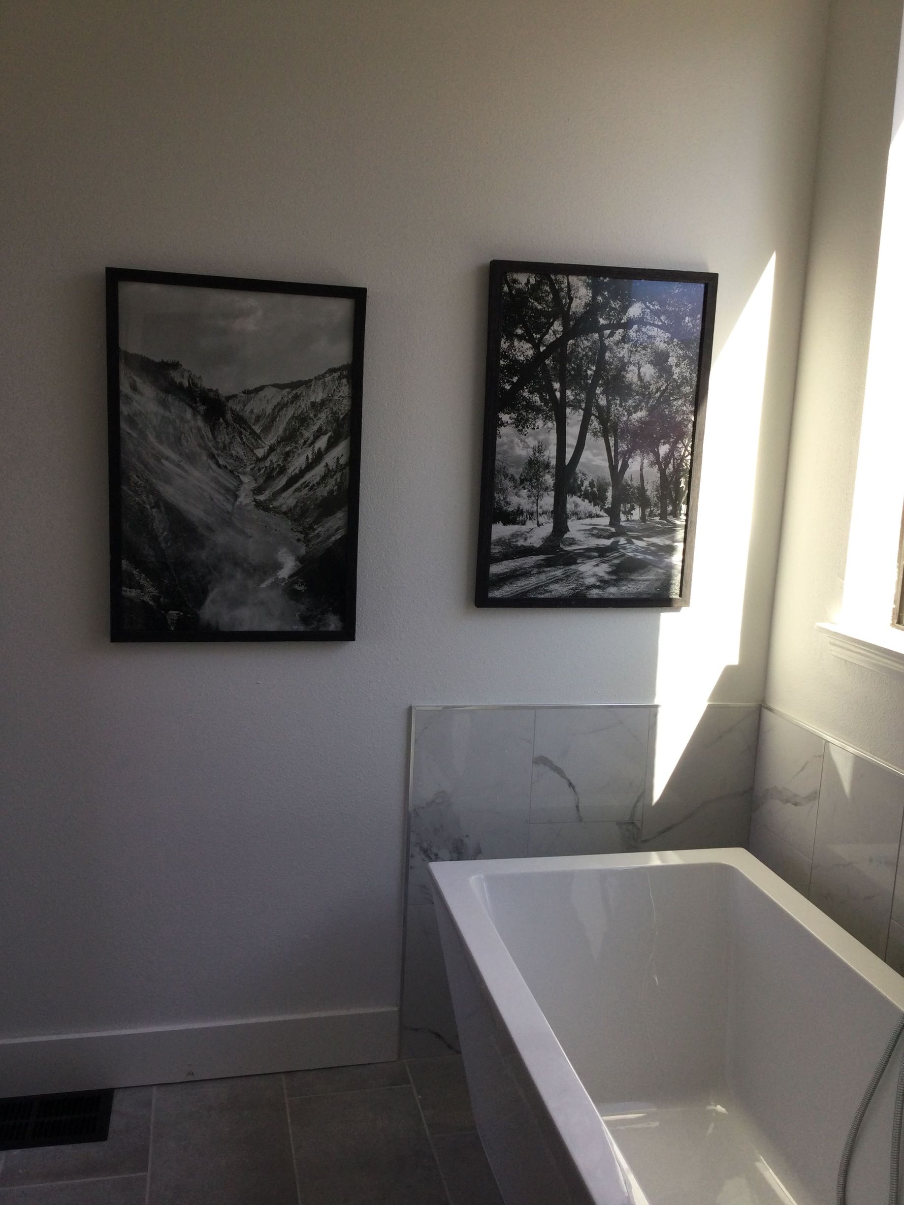 A bathroom with a bathtub and two pictures on the wall