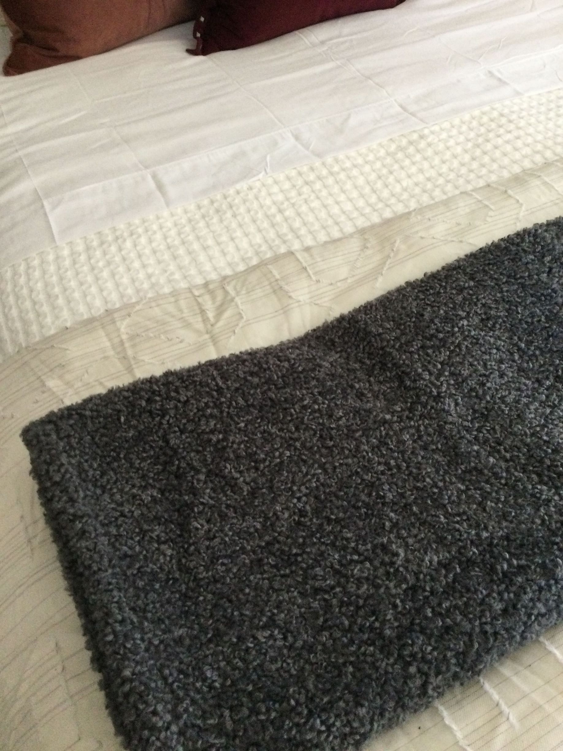 A gray rug is laying on top of a bed.