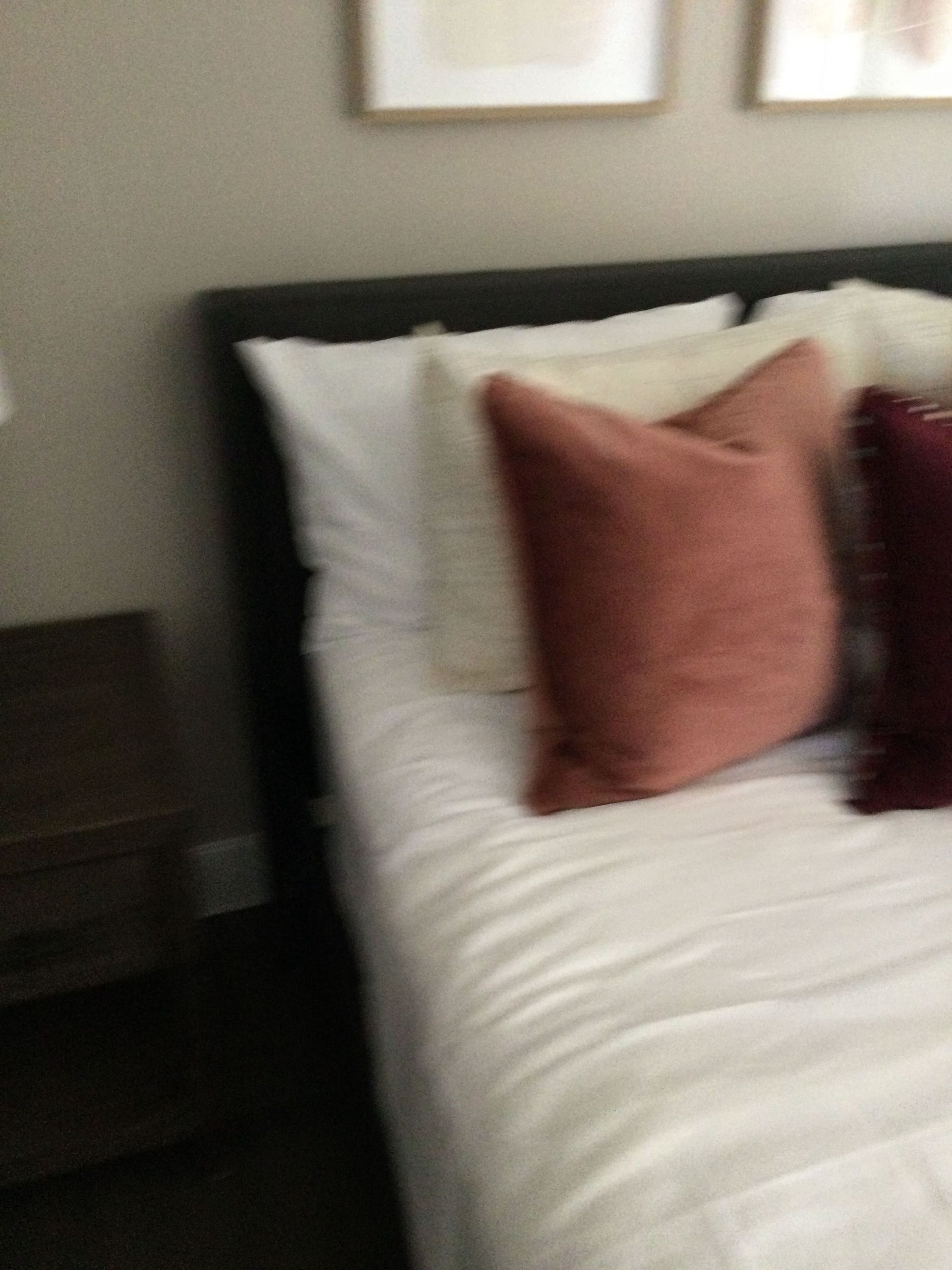 A bed with white sheets and pillows in a bedroom