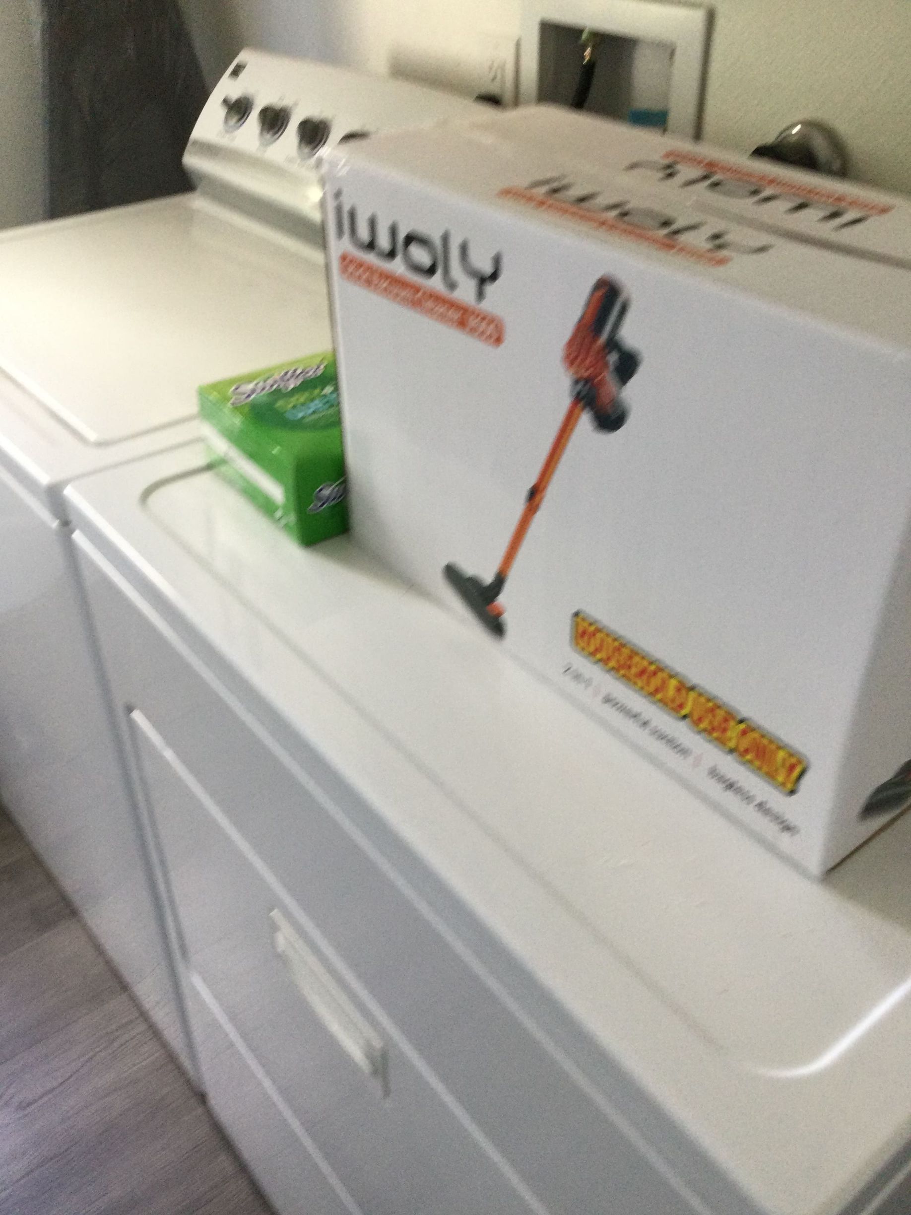 A box of woly vacuum cleaner sits on top of a washer and dryer