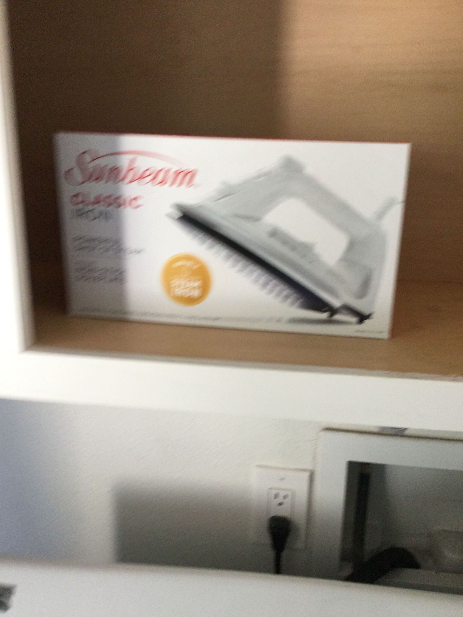 A box of a sunbeam classic iron sits on a shelf
