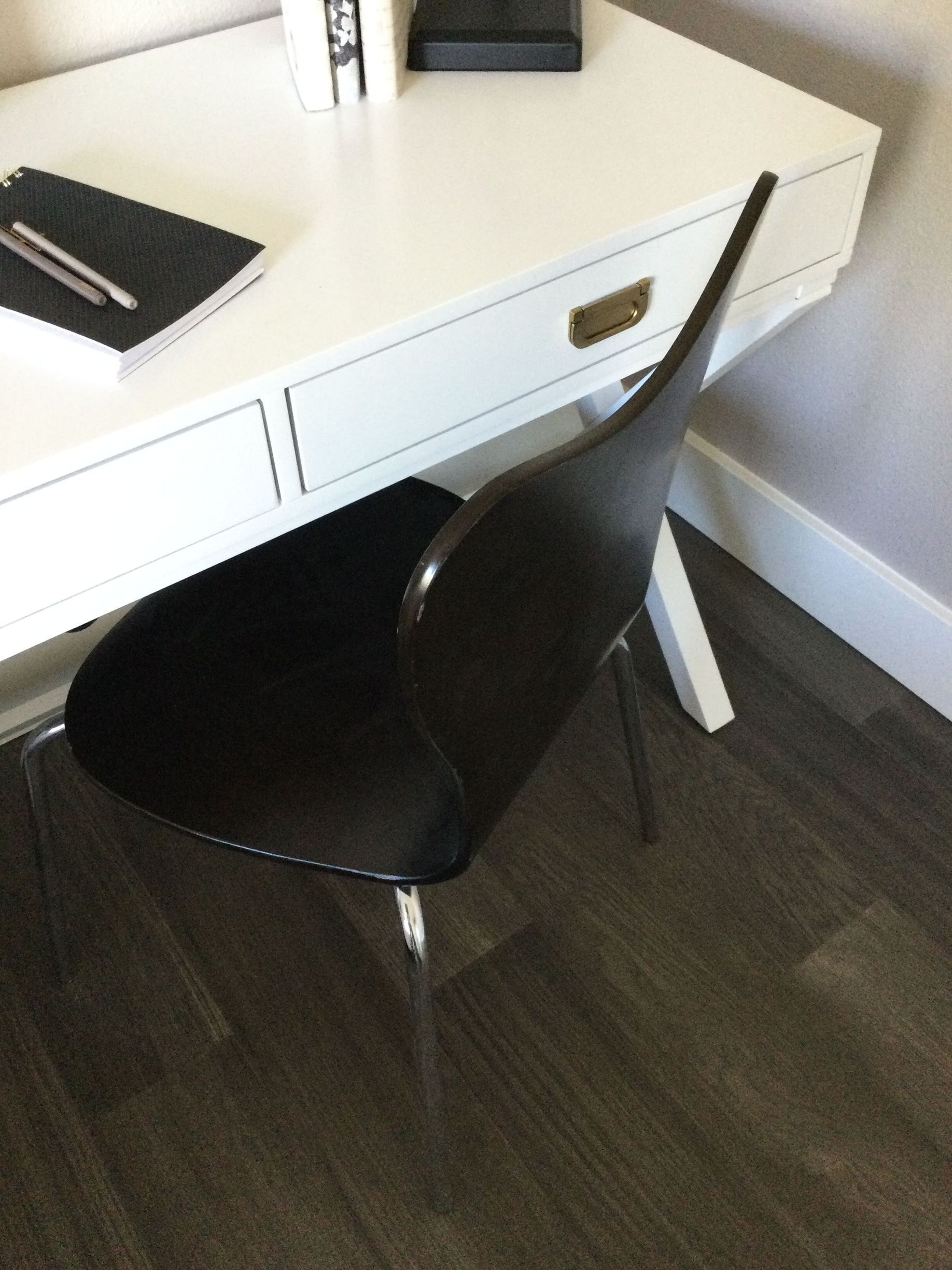 A black chair sits in front of a white desk