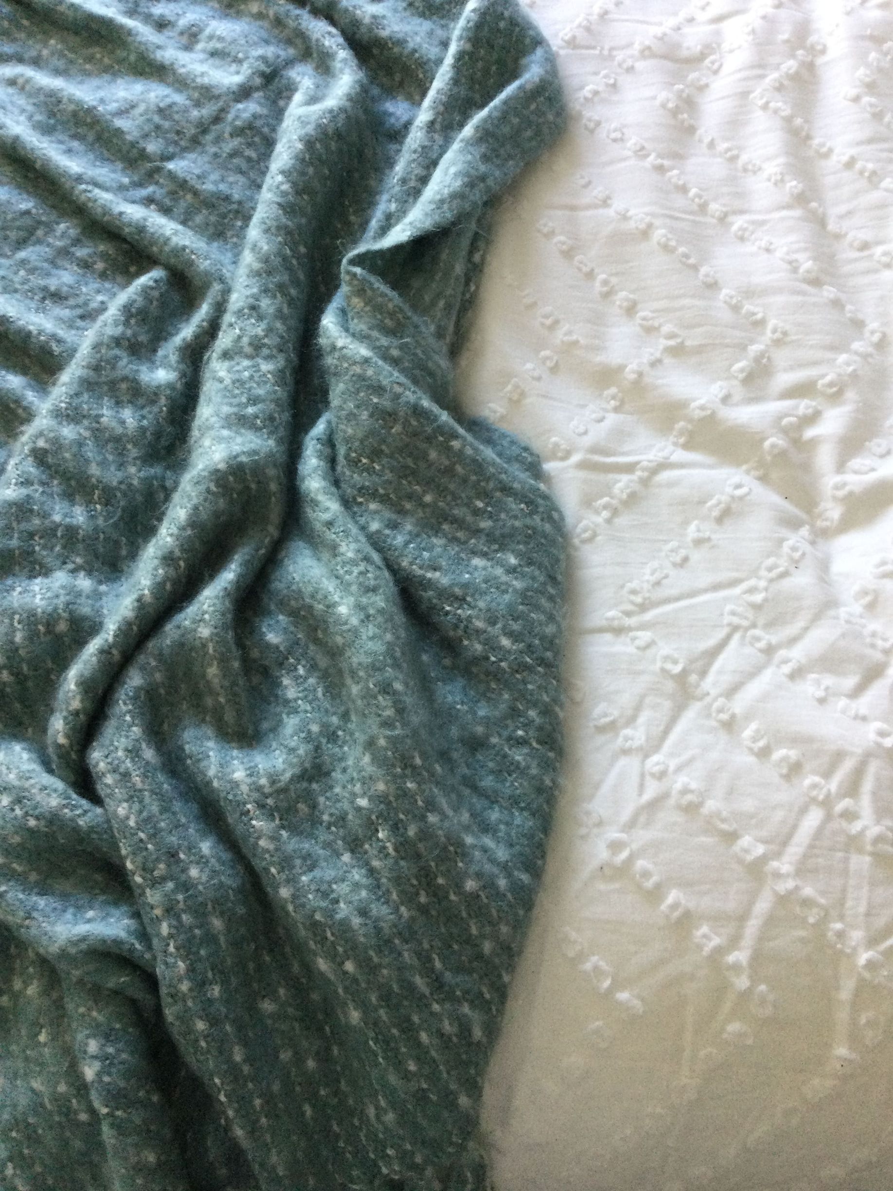 A blue blanket is laying on top of a white bed.