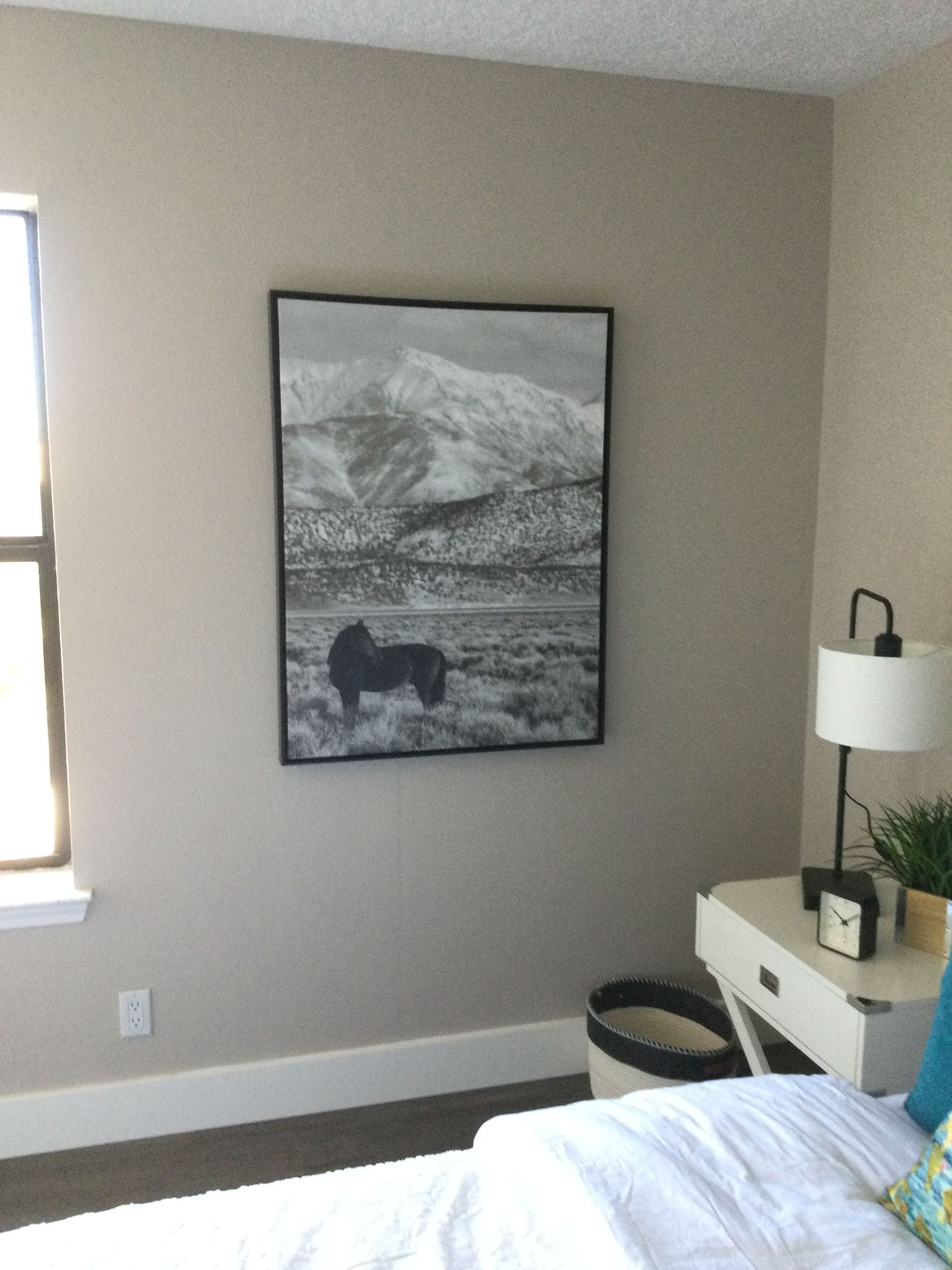 A bedroom with a picture of a horse on the wall