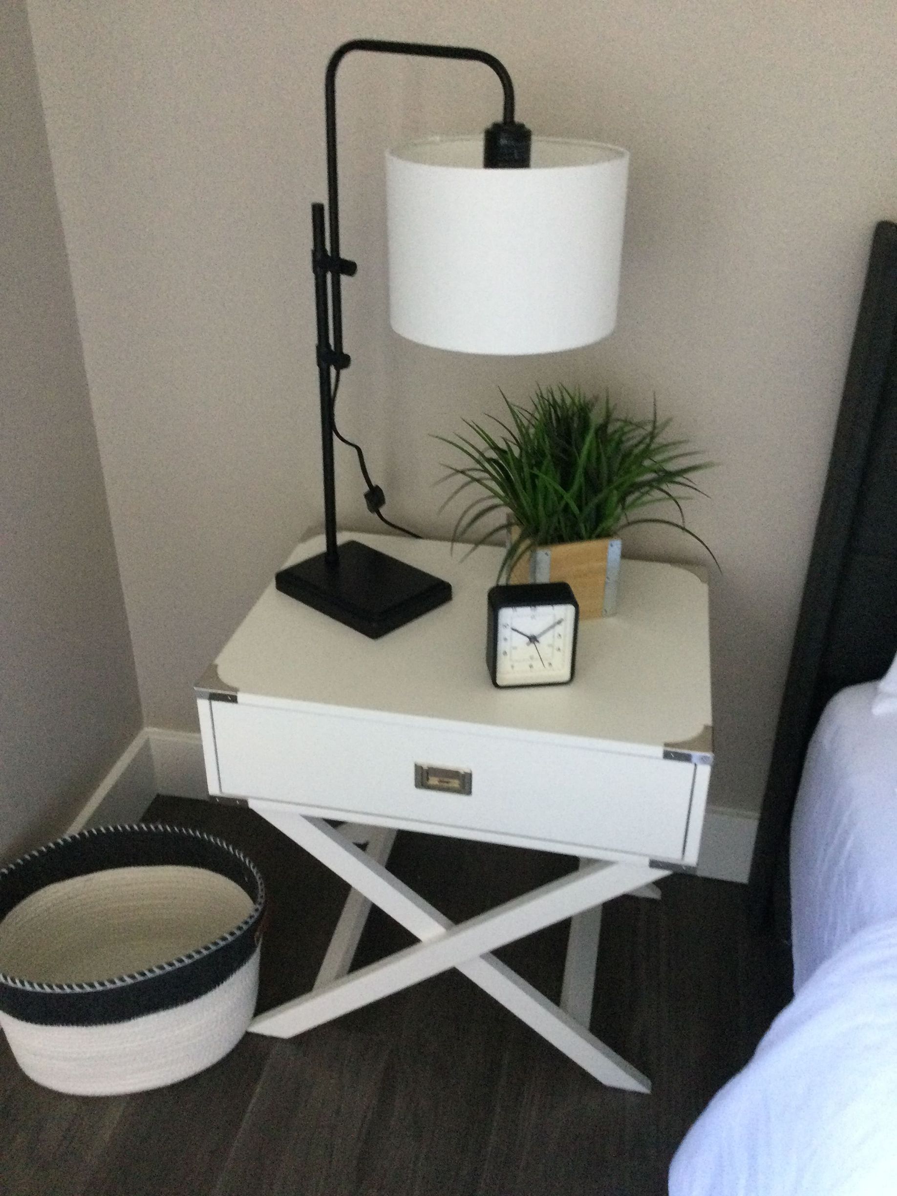 A nightstand with a lamp and a clock on it