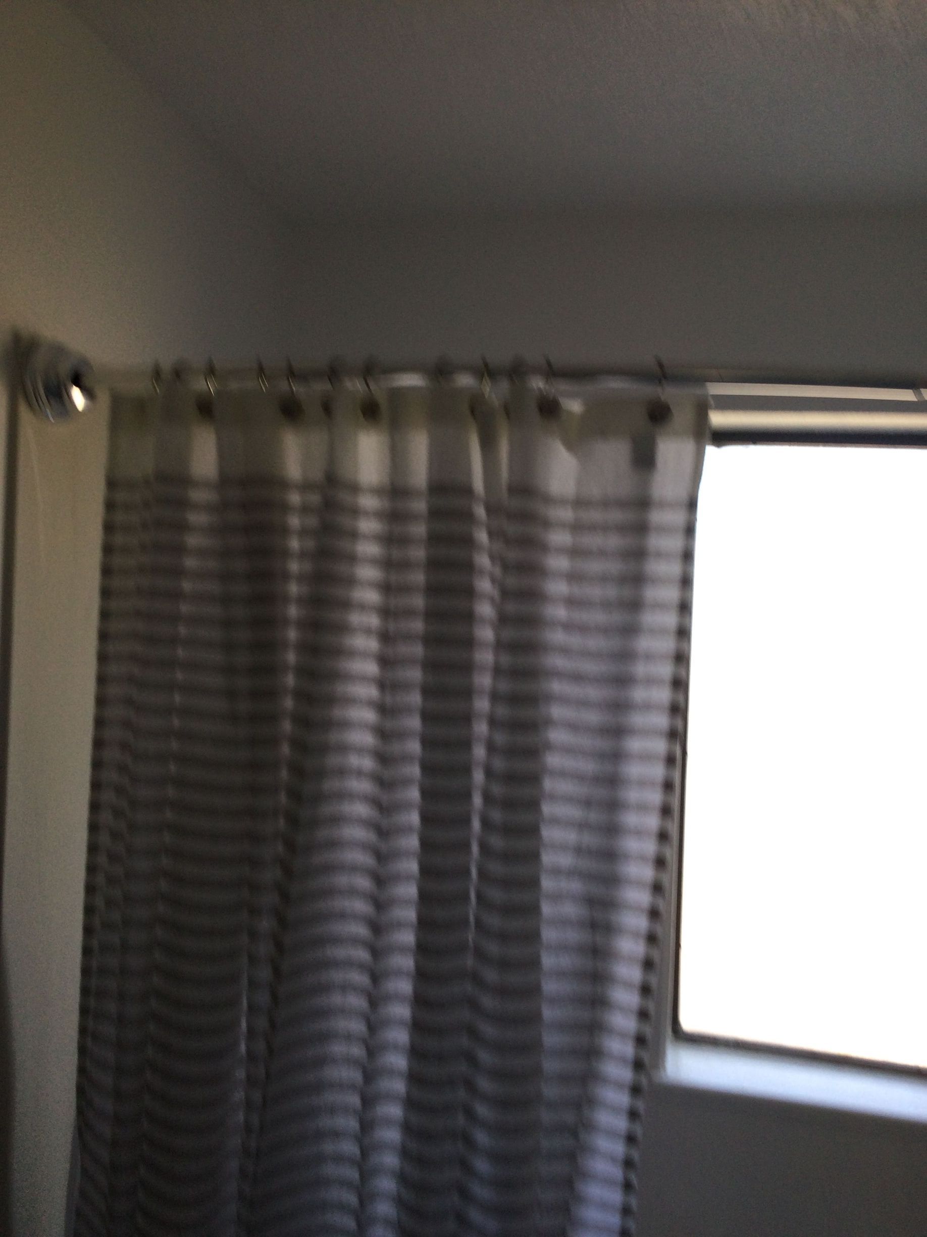 A bathroom with a shower curtain and a window