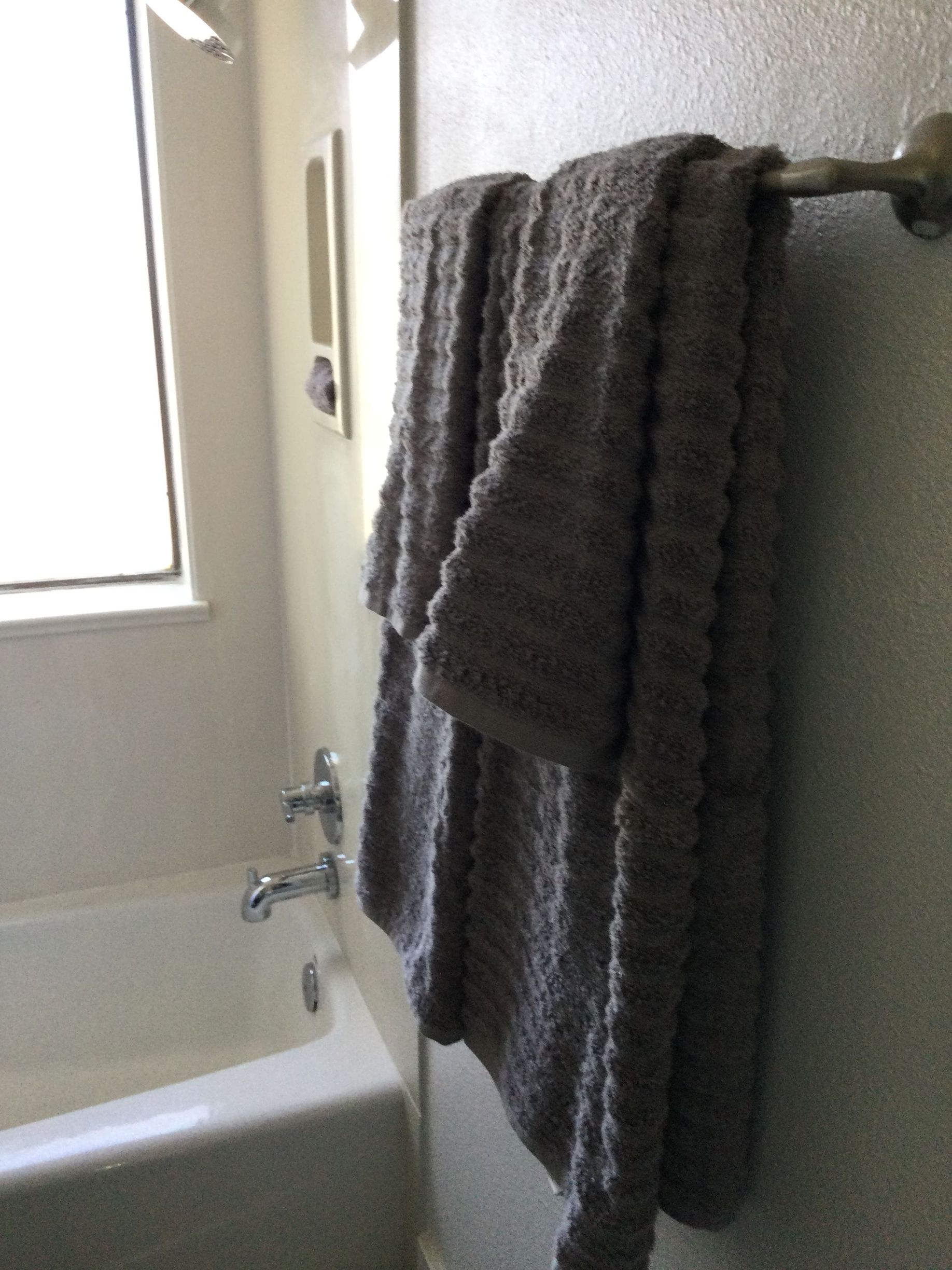 A bathroom with a bathtub and towels hanging on the wall