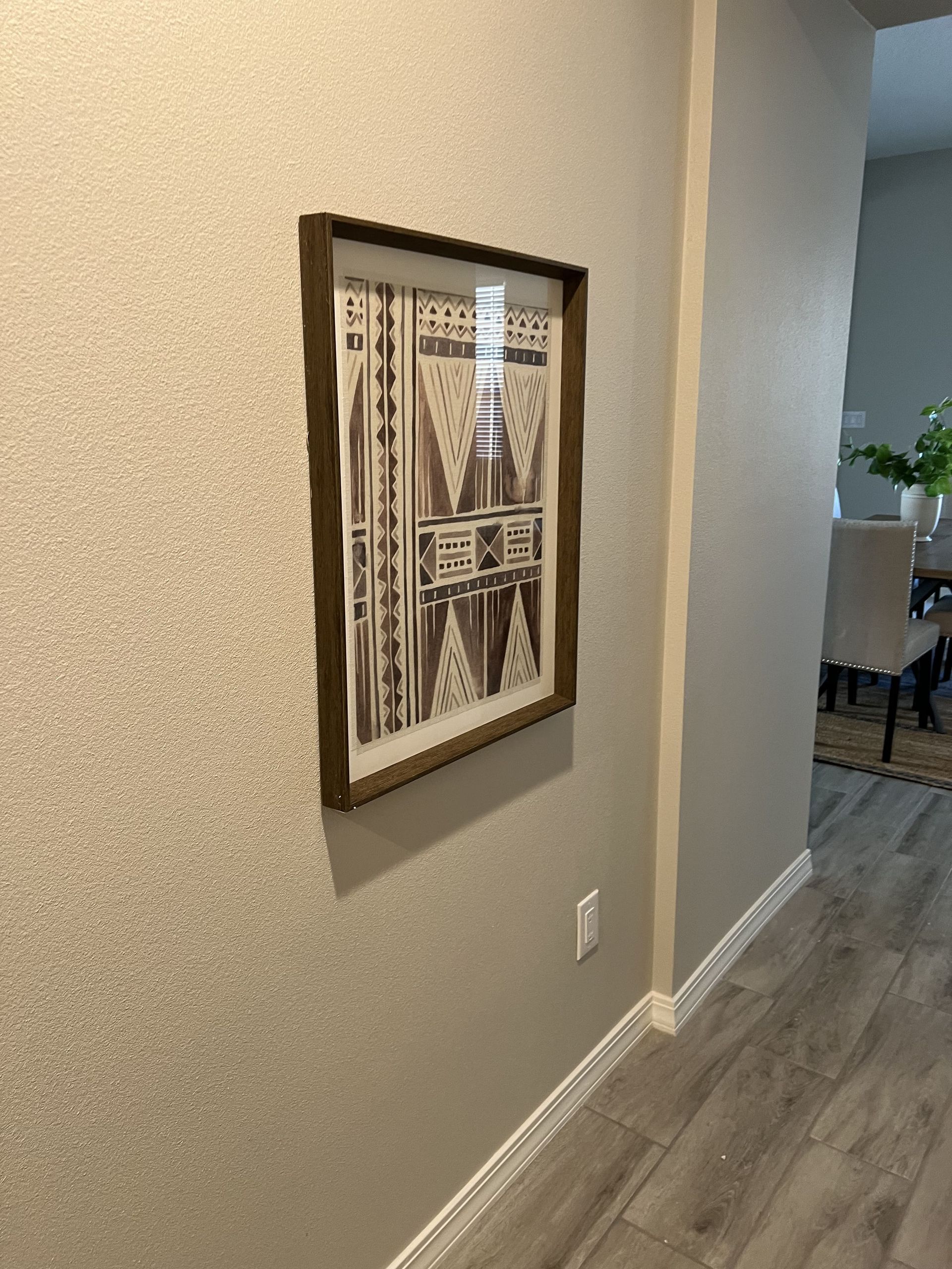 A framed picture is hanging on a wall in a hallway.