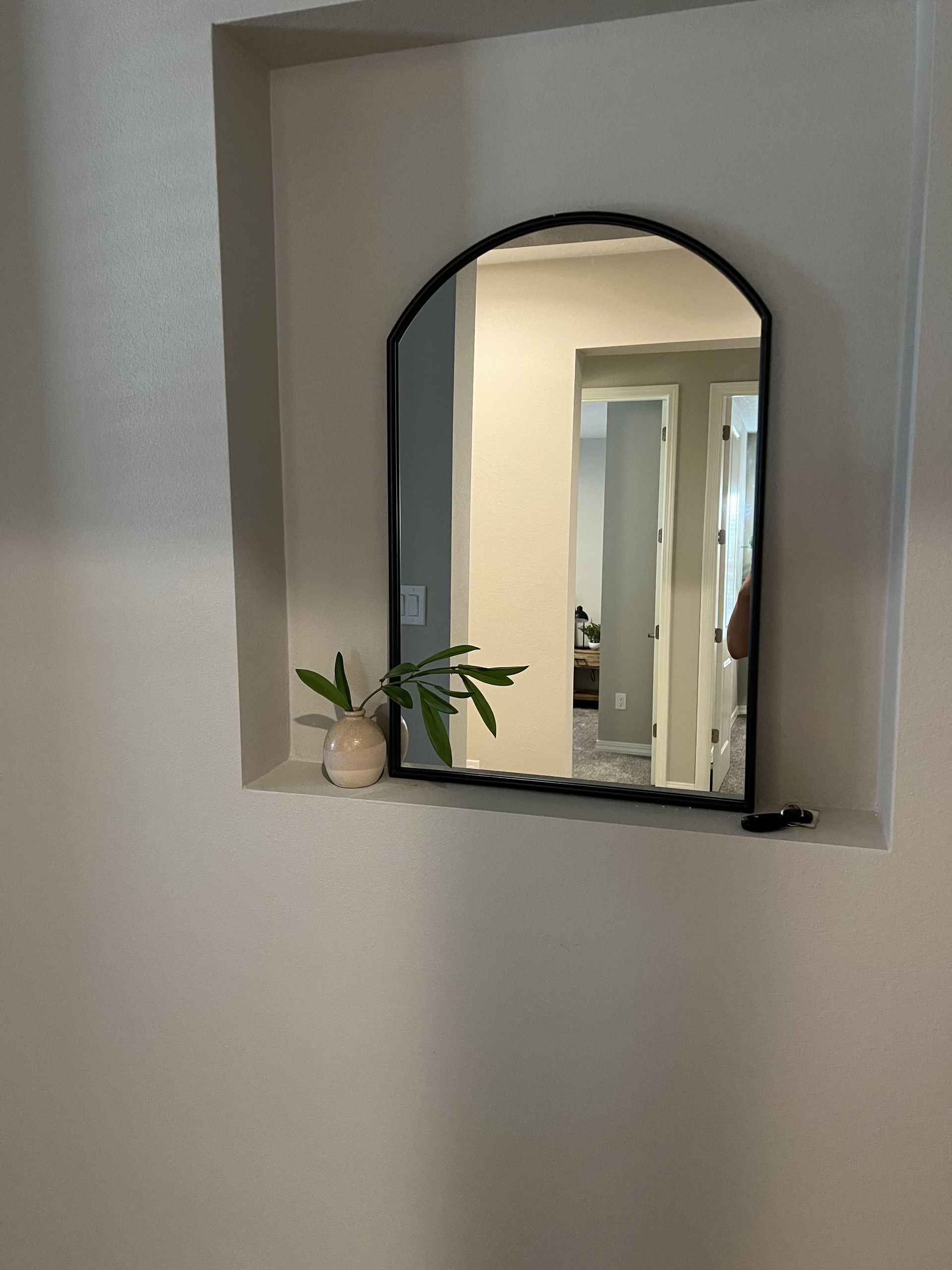A mirror is hanging in a niche on a wall.