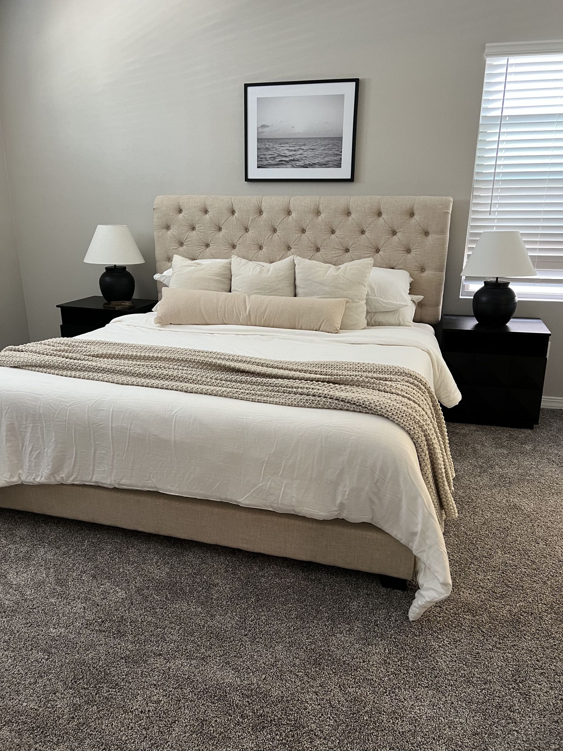 A bedroom with a bed , nightstands , lamps and a picture on the wall.