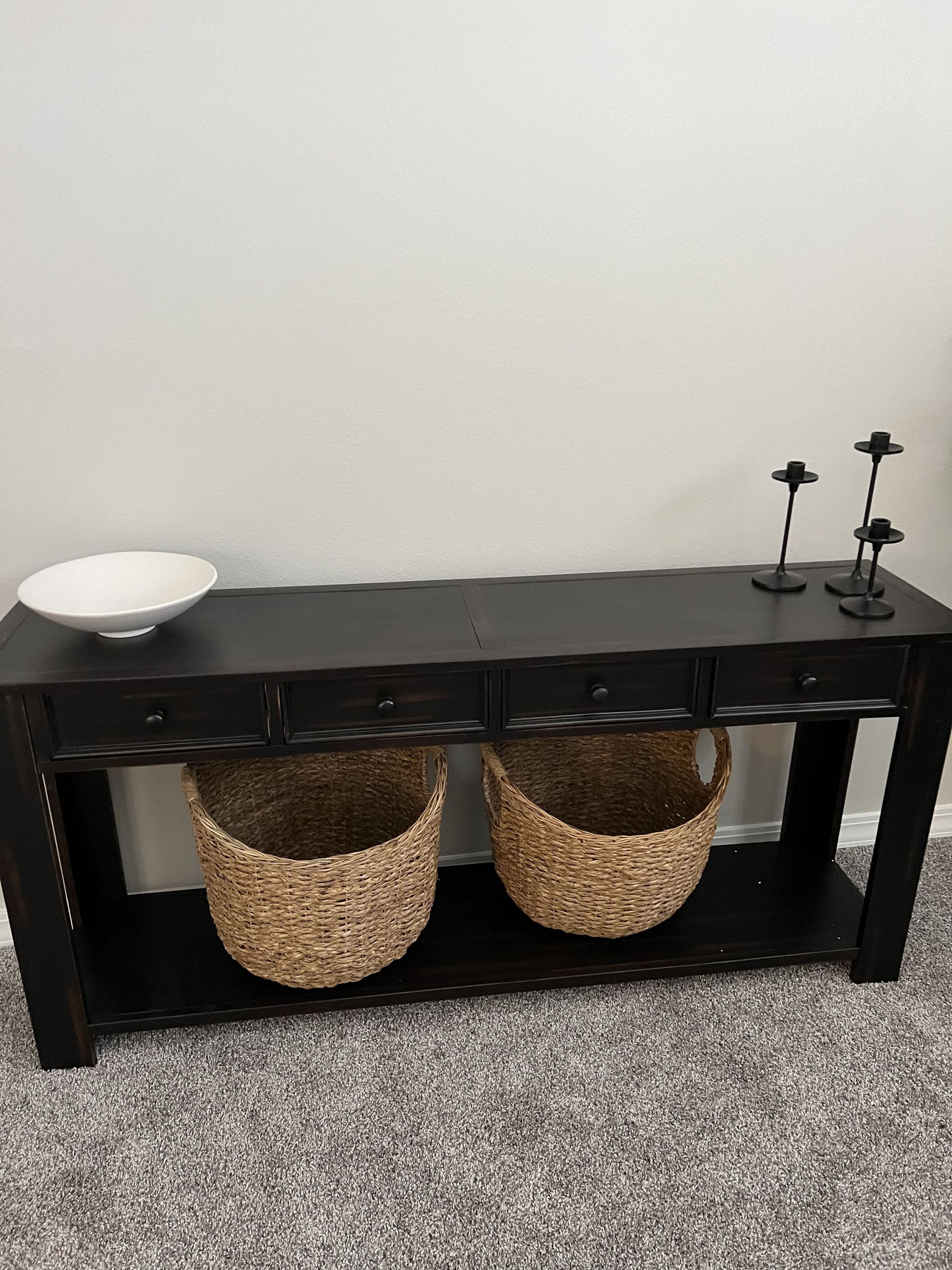 A black table with two baskets and candles on it.